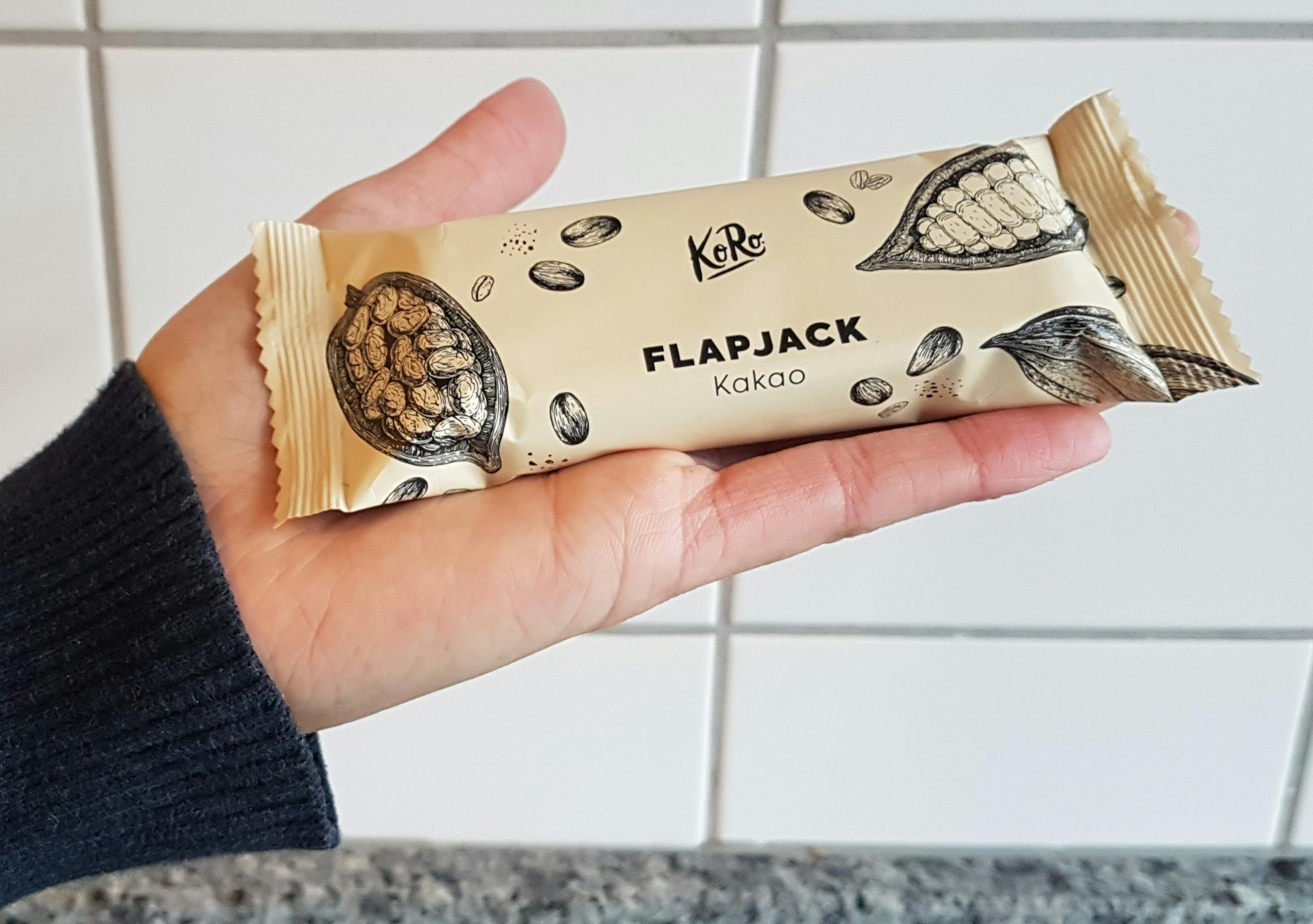 une personne tient une barre de chocolat flapjack au cacao