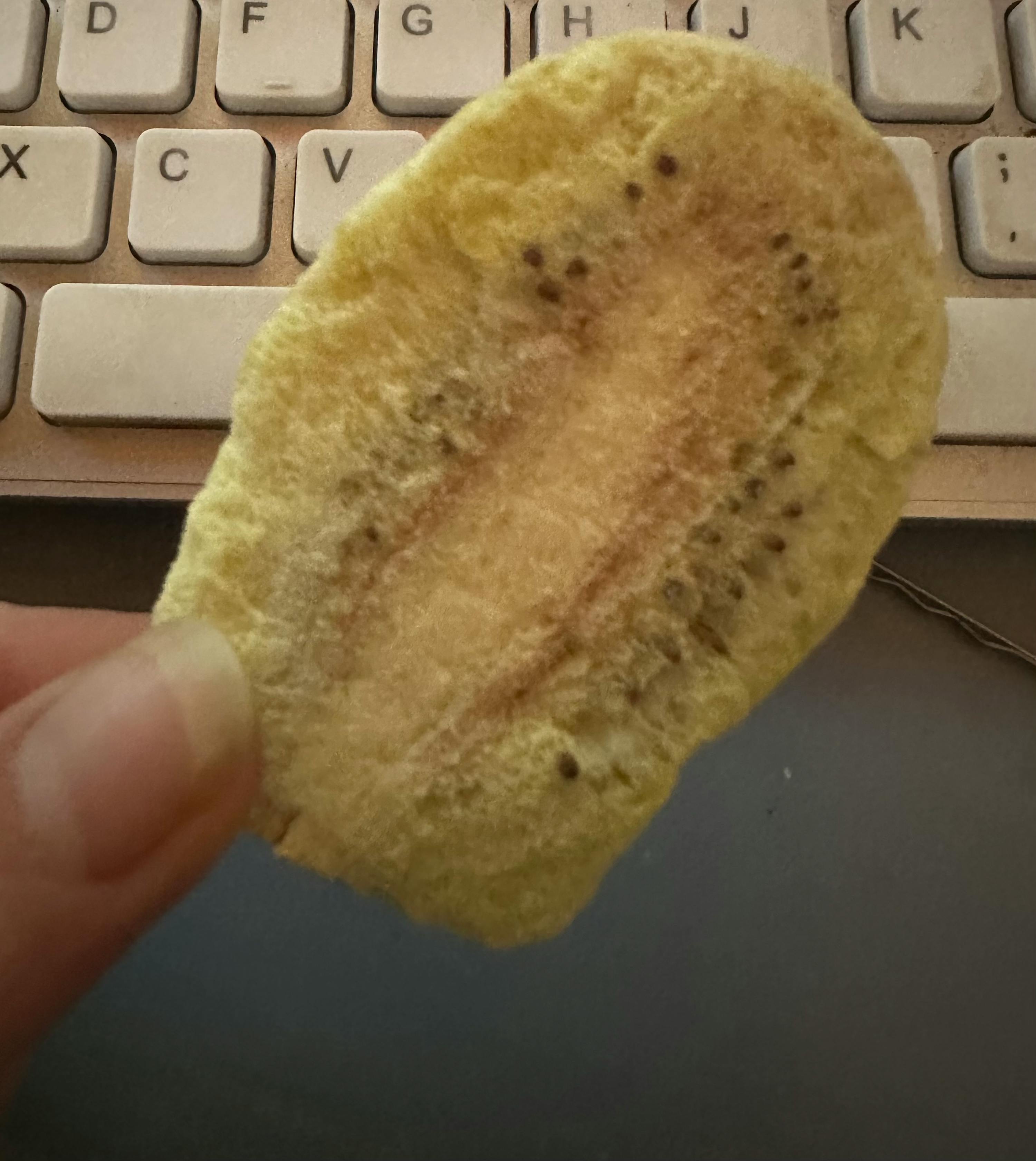 eine Person hält vor einer Tastatur ein Stück Essen