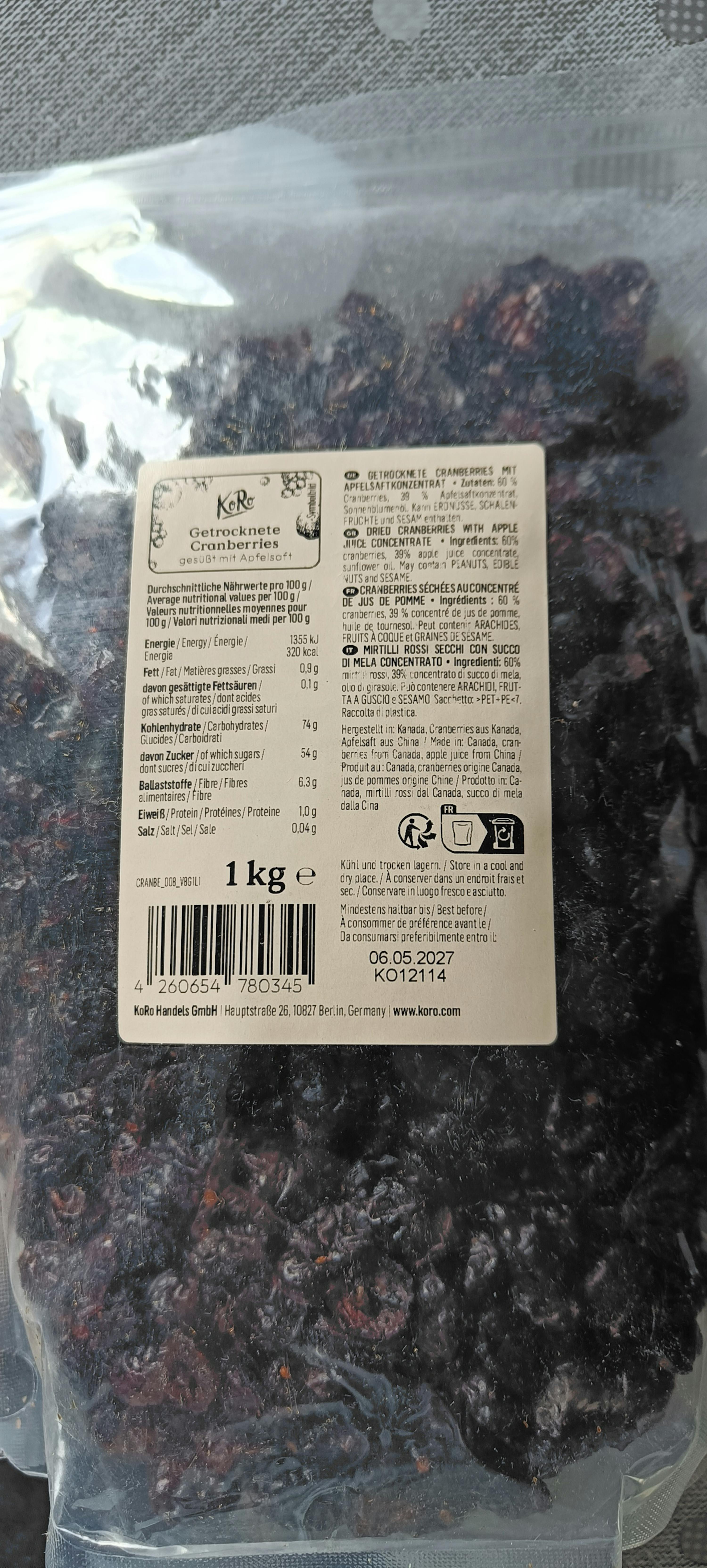 eine transparente plastiktüte mit getrockneten cranberries, gesüßt mit apfelsaft, und einem weißen etikett mit produktinformationen und einem gewicht von 1 kg.