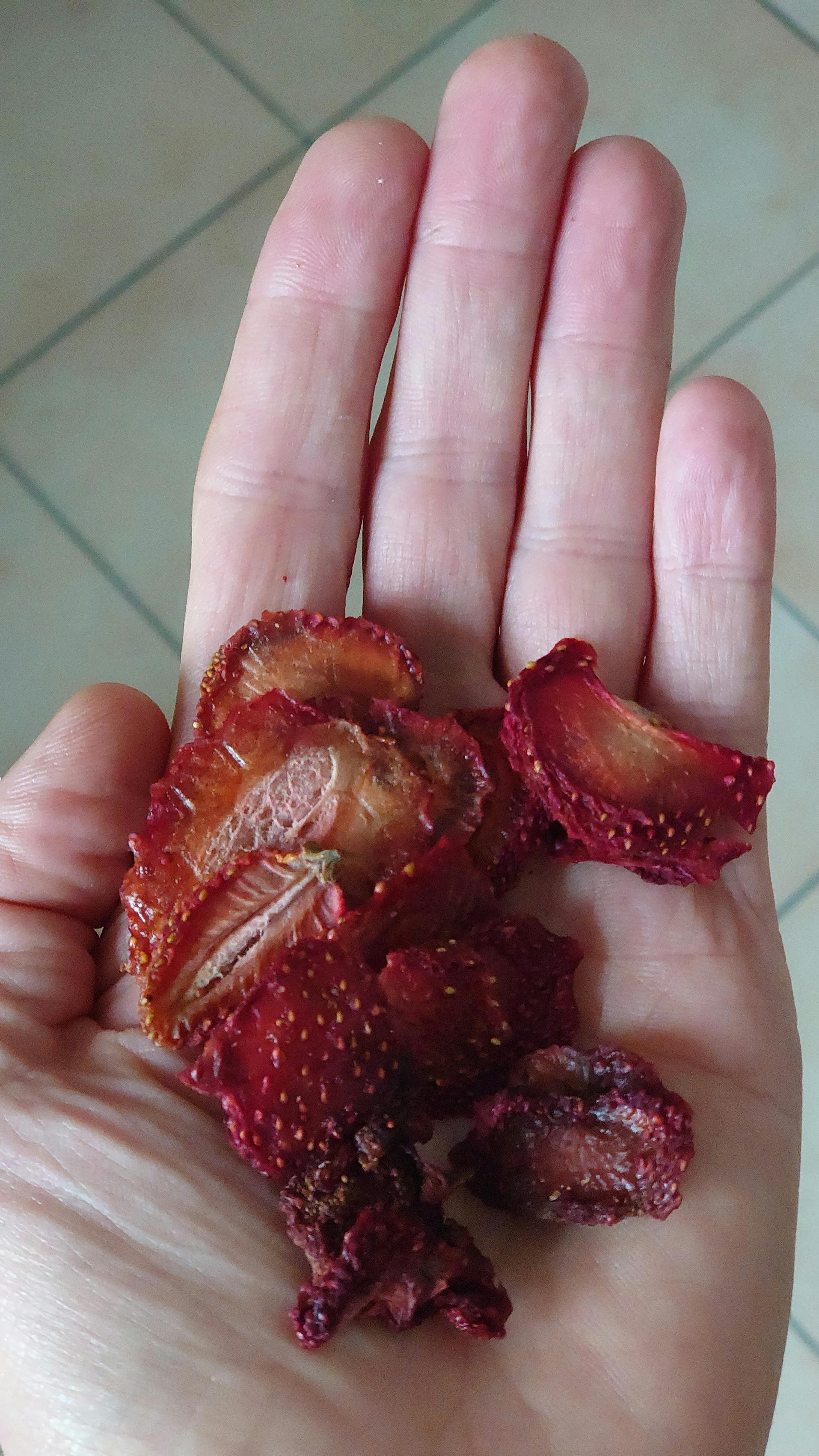 a person holding a handful of dried strawberries
