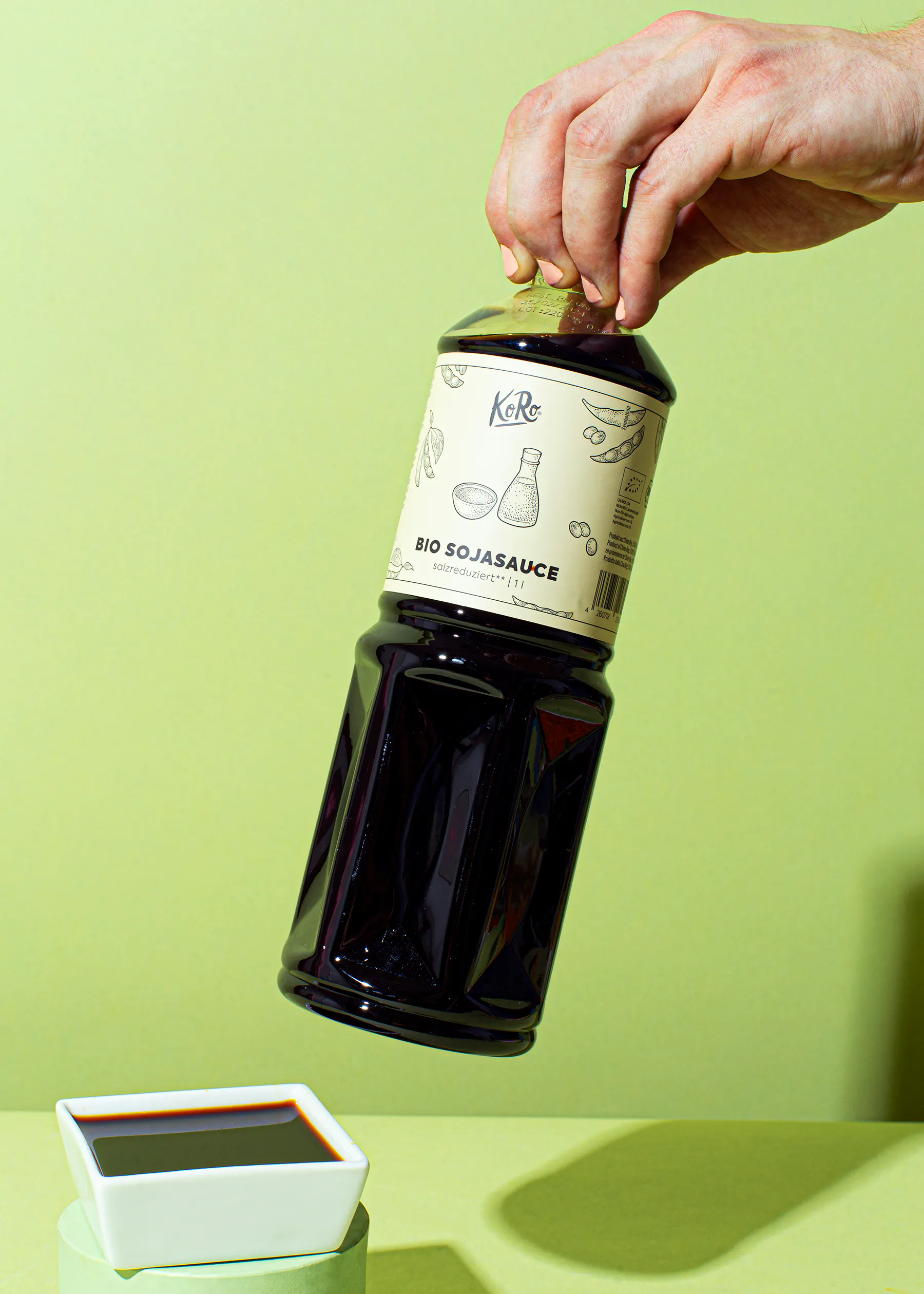a bottle of bio sojasauce is being poured into a white bowl