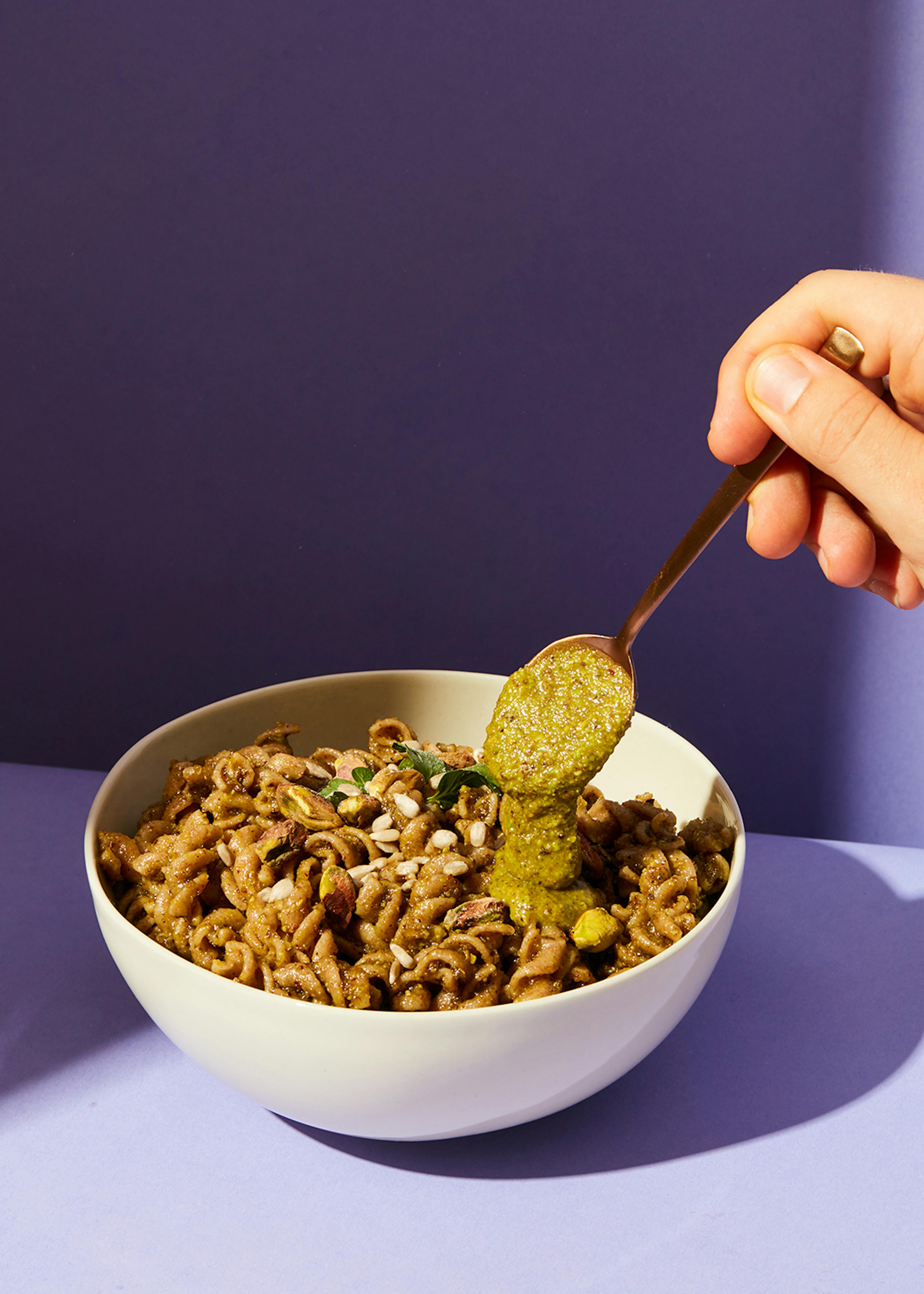 a person is dipping a spoon into a bowl of pasta