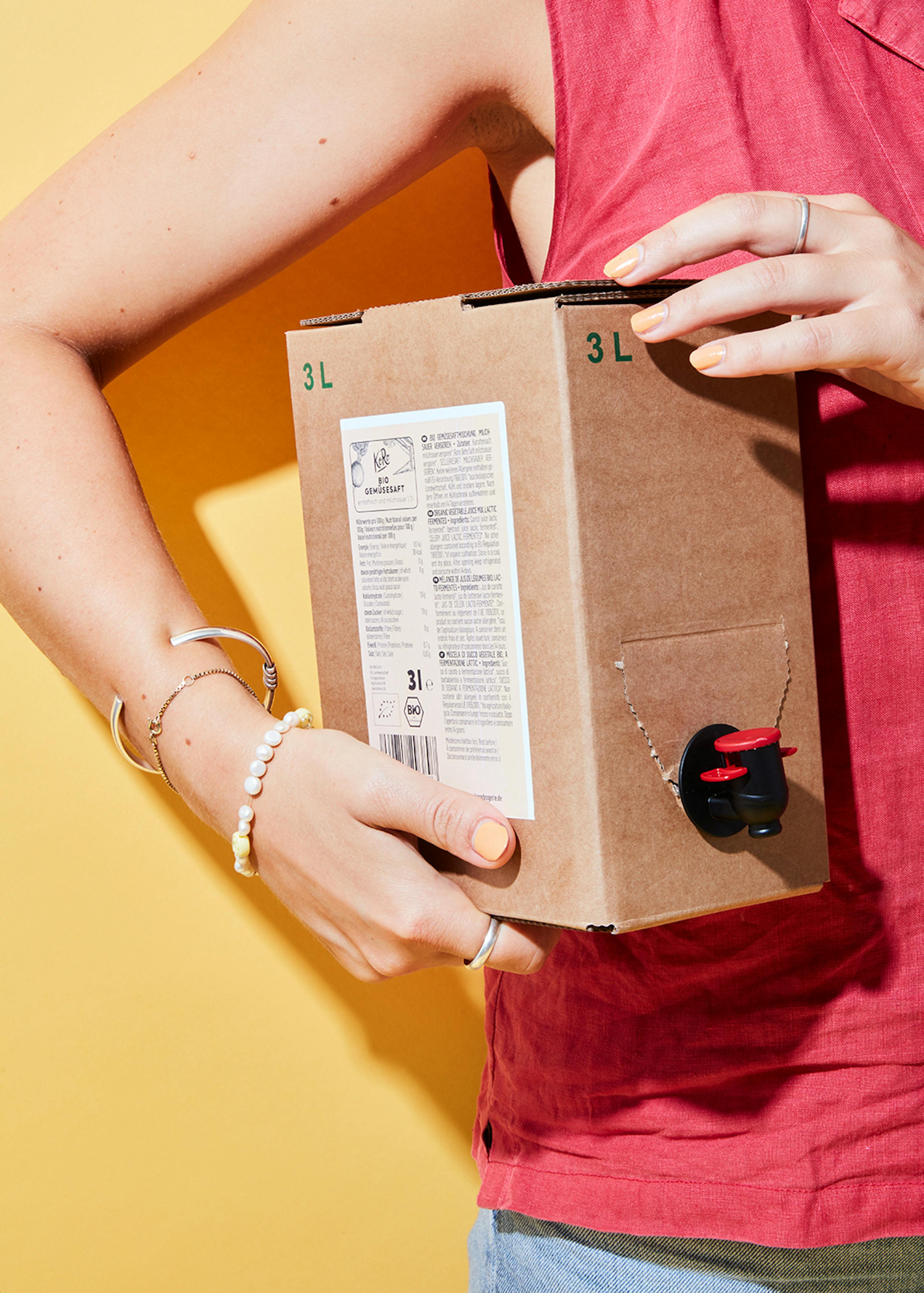 una donna tiene in mano una scatola di cartone con la scritta 3l