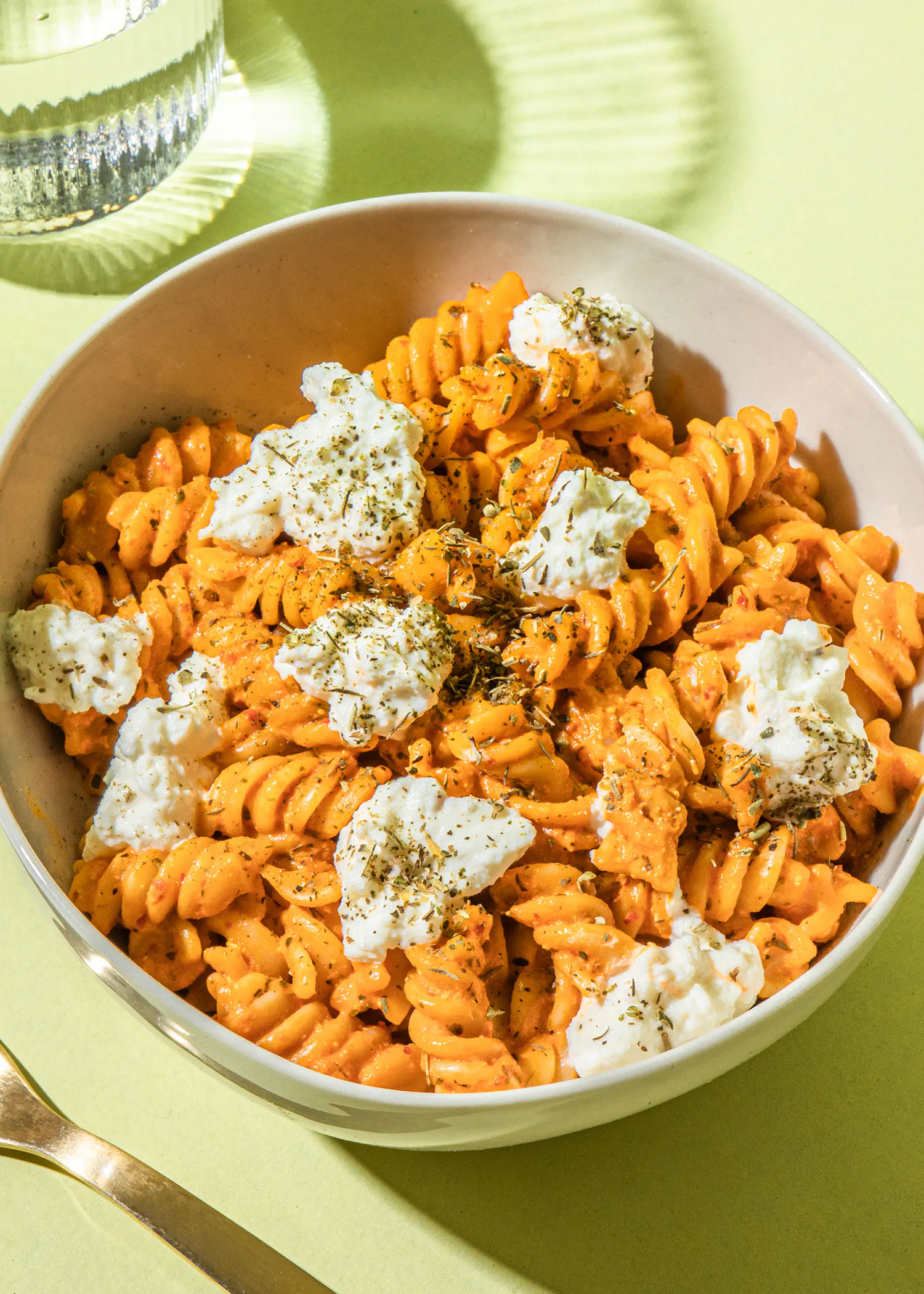 un bol de pâtes avec de la ricotta et des herbes sur une table