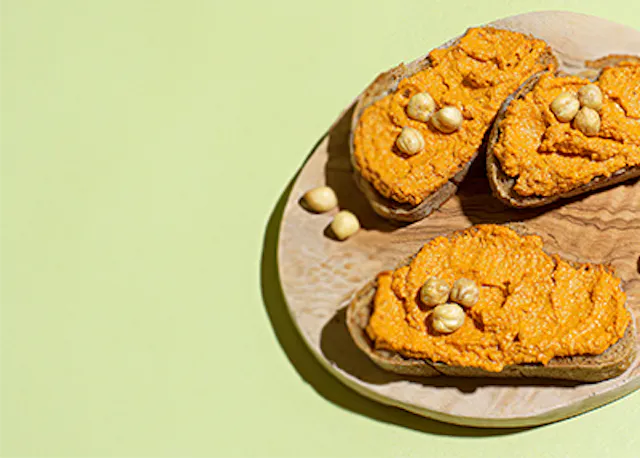 trois tranches de pain avec du fromage et des noisettes sur une planche à découper en bois