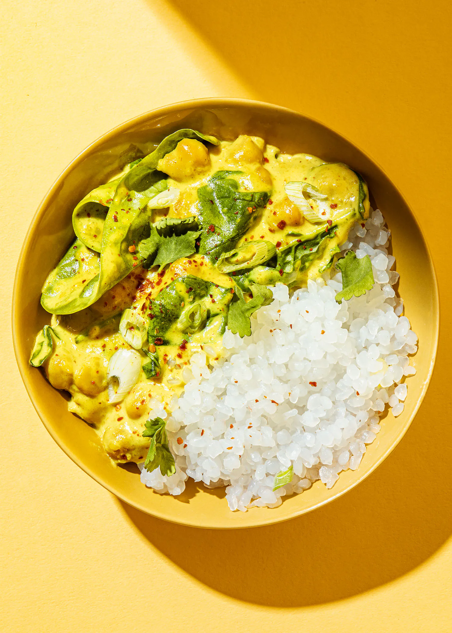 eine gelbe schüssel mit reis und curry auf einem gelben hintergrund