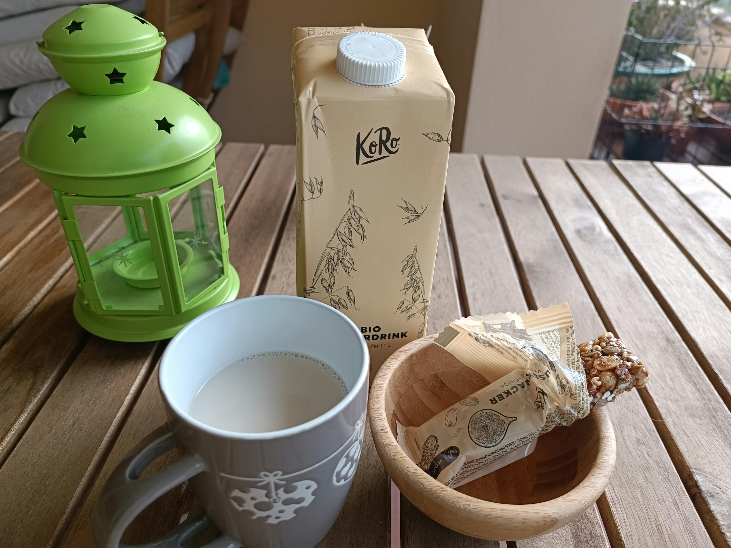 une bouteille de boisson à l' avoine est assise sur une table en bois à côté d' une tasse