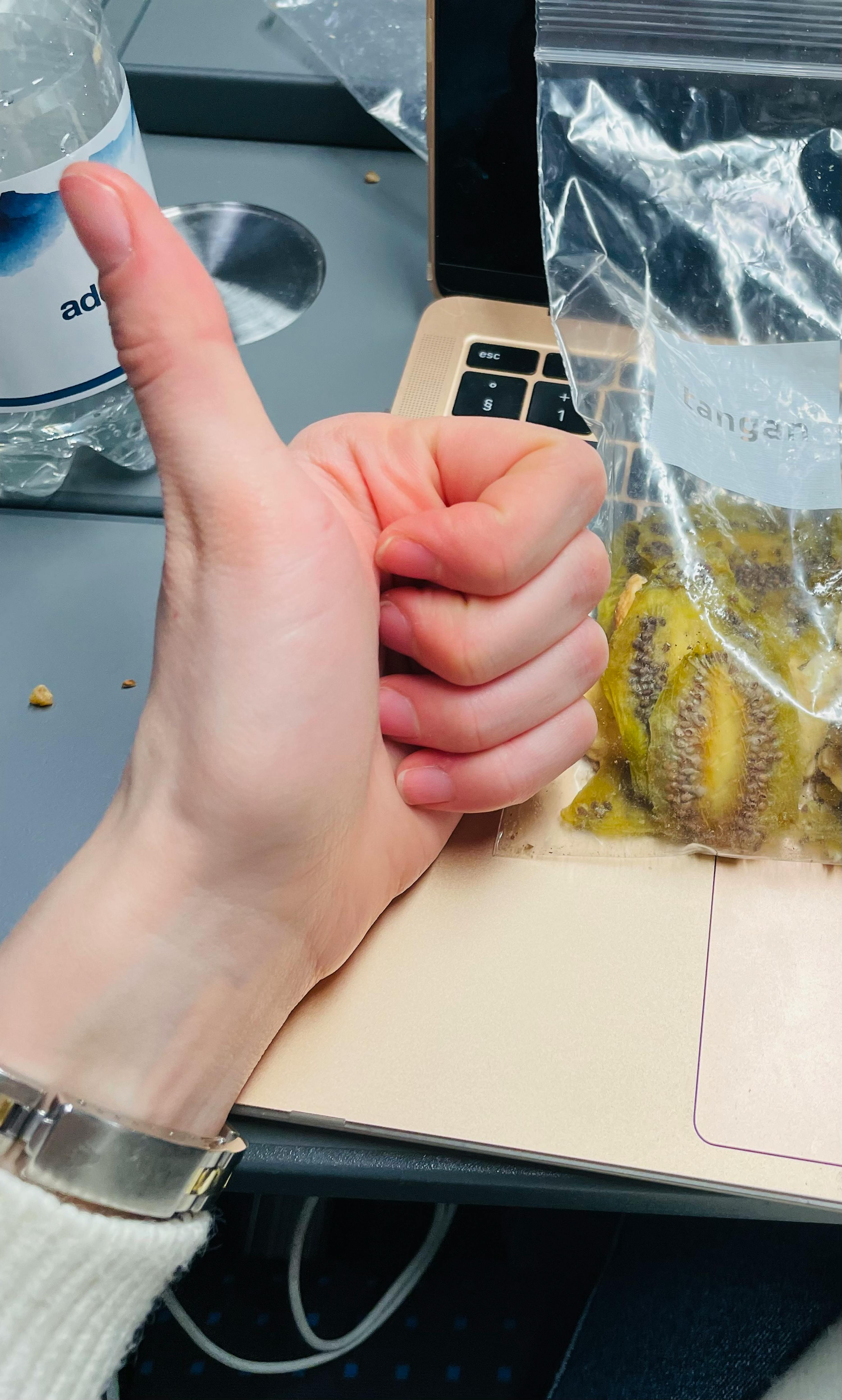 eine Person gibt einen Daumen nach oben neben einem Laptop