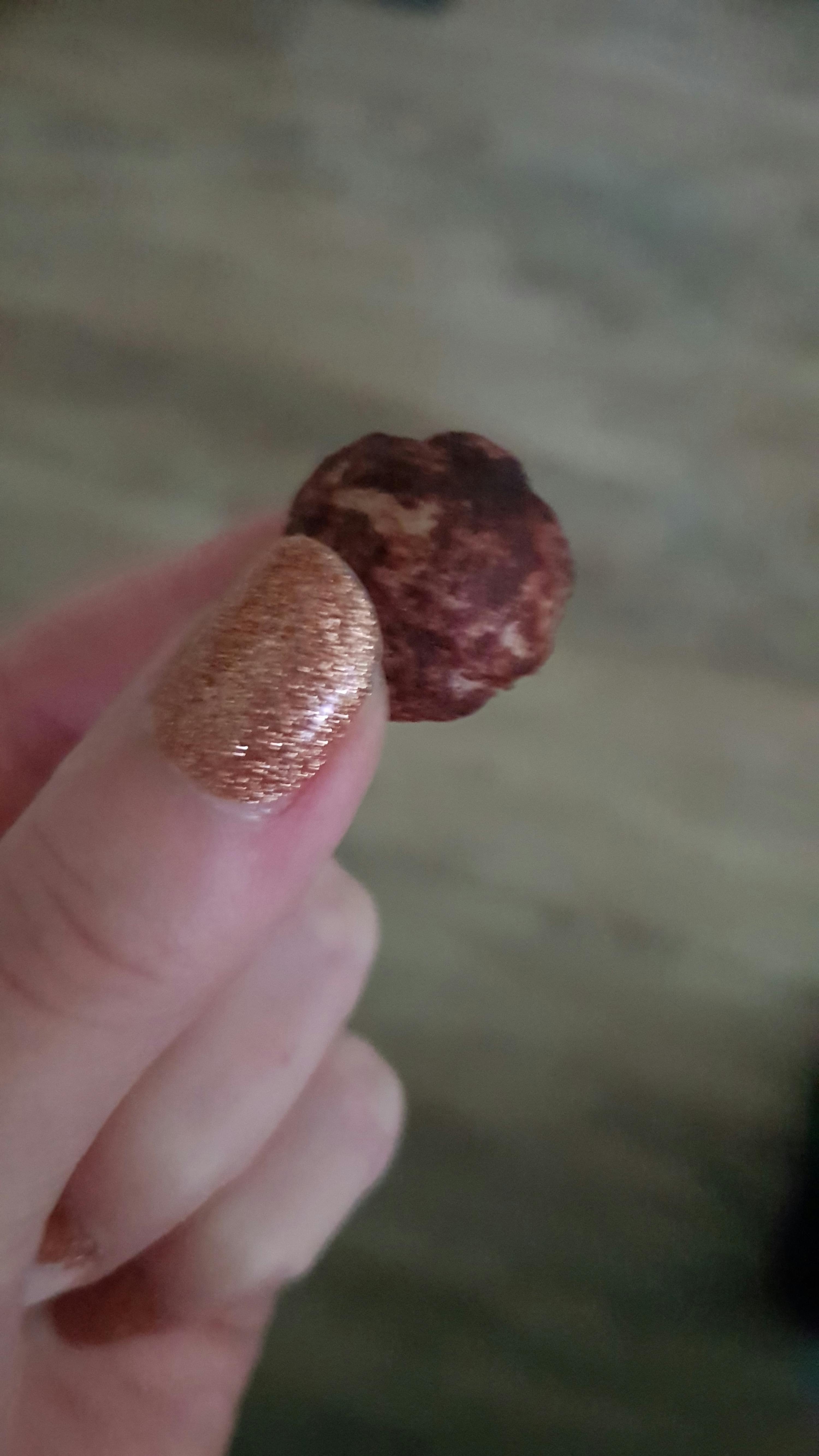 eine Person mit goldenen Nägeln hält einen Schokoriegel in der Hand