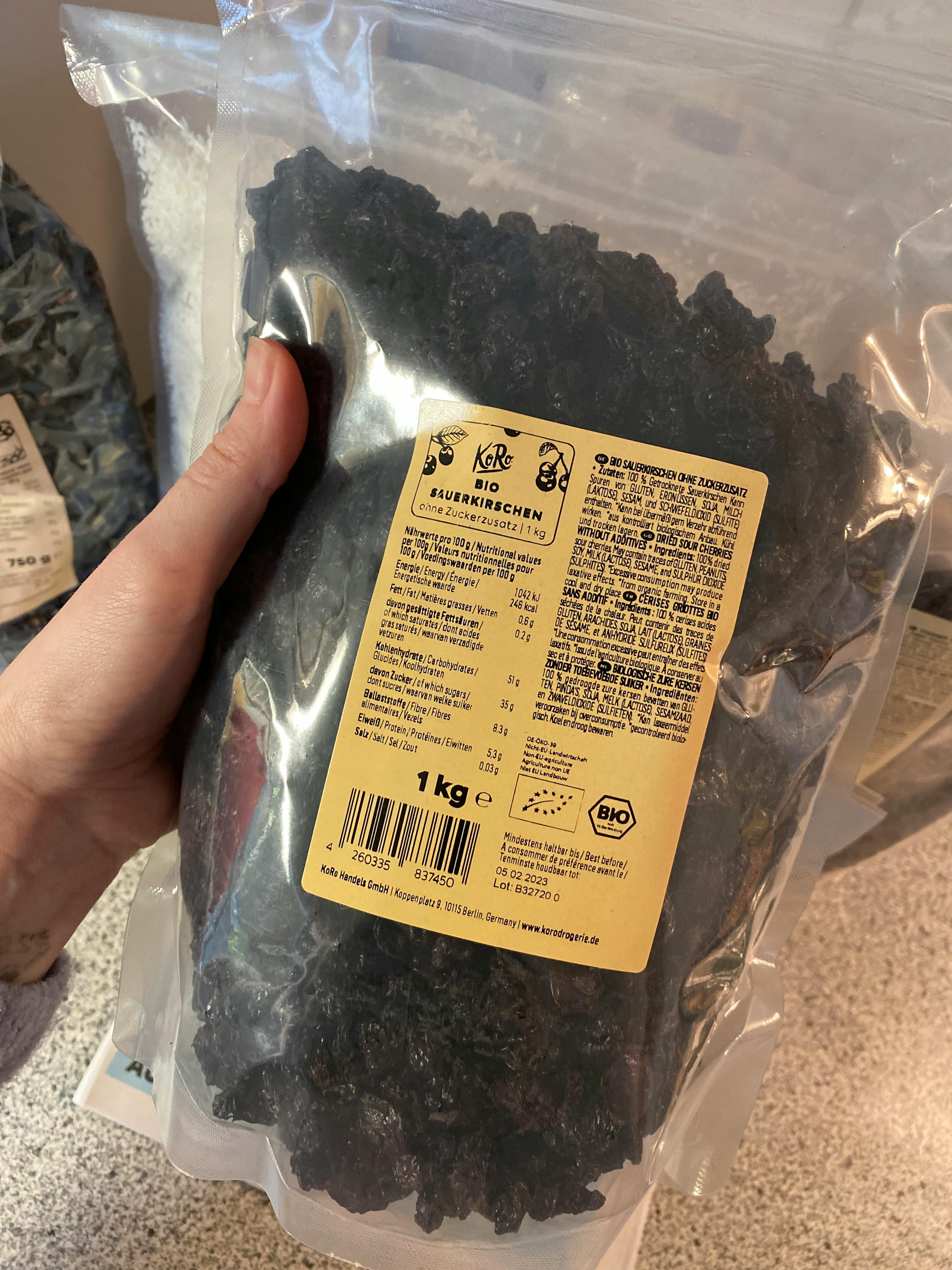 une personne tient un sac de raisins noirs bio