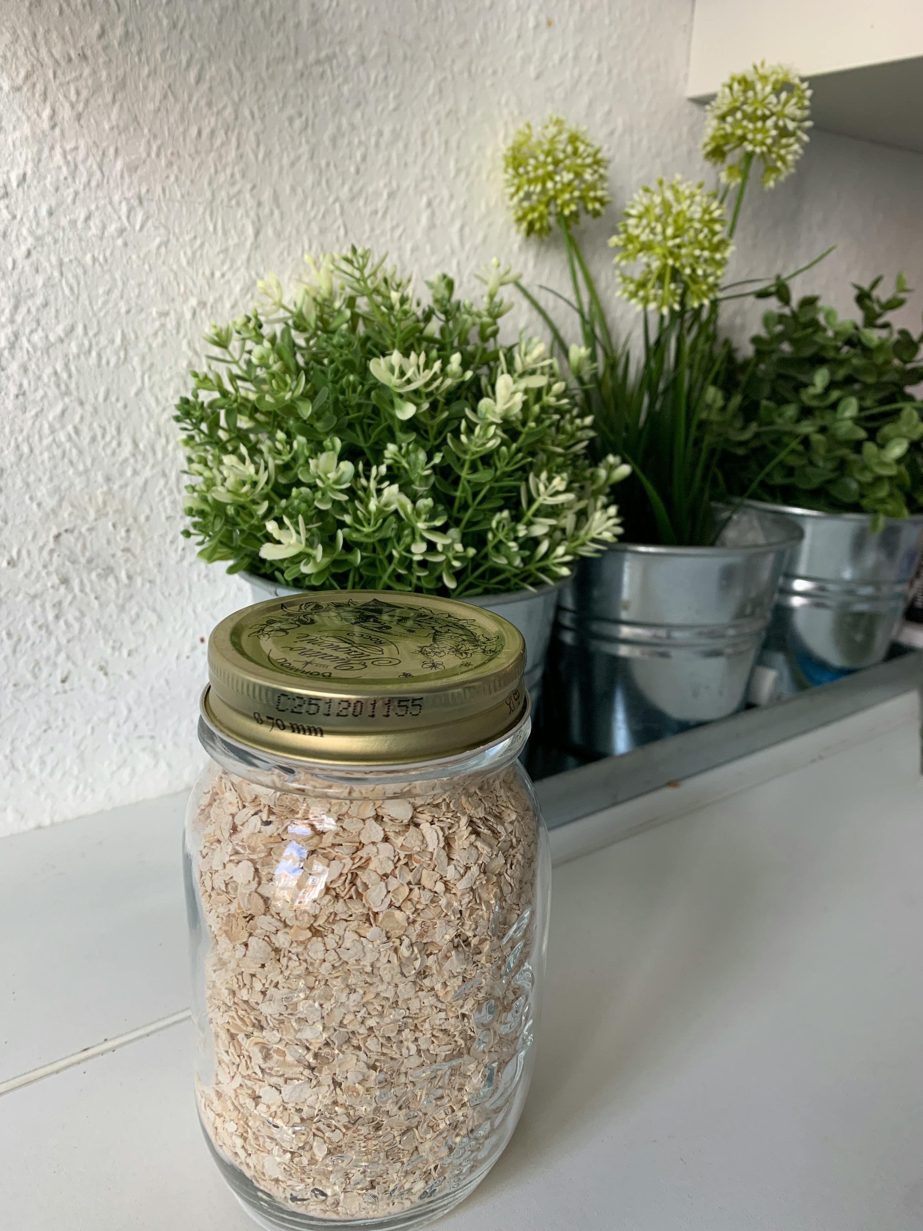 un bocal en verre rempli de flocons d' avoine avec un couvercle doré