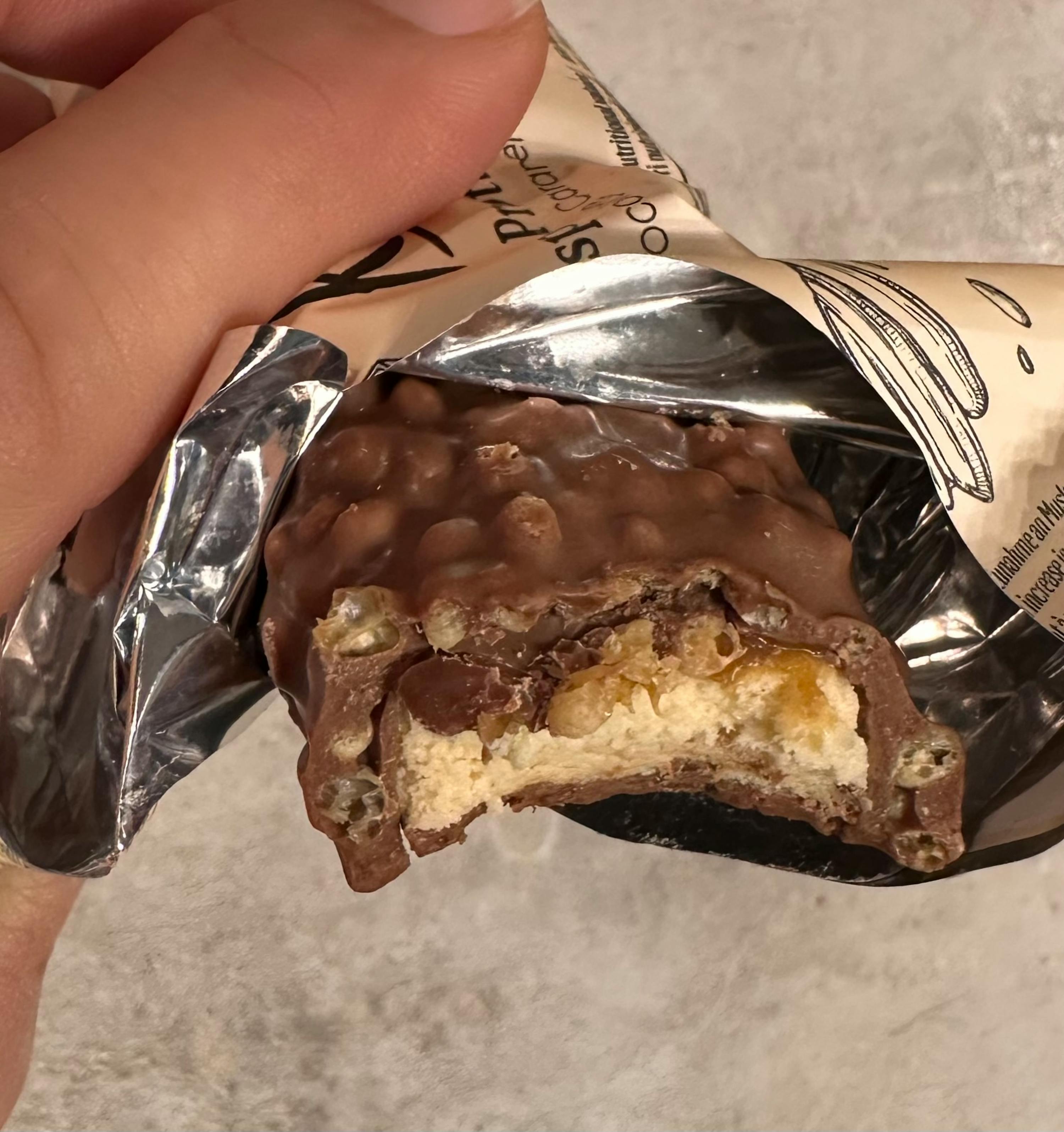 eine Person hält eine Schokoladenstange mit einem Stück genommen