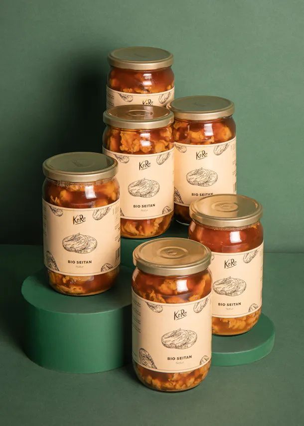 six bocaux de bio seitan sont empilés les uns sur les autres sur une table verte