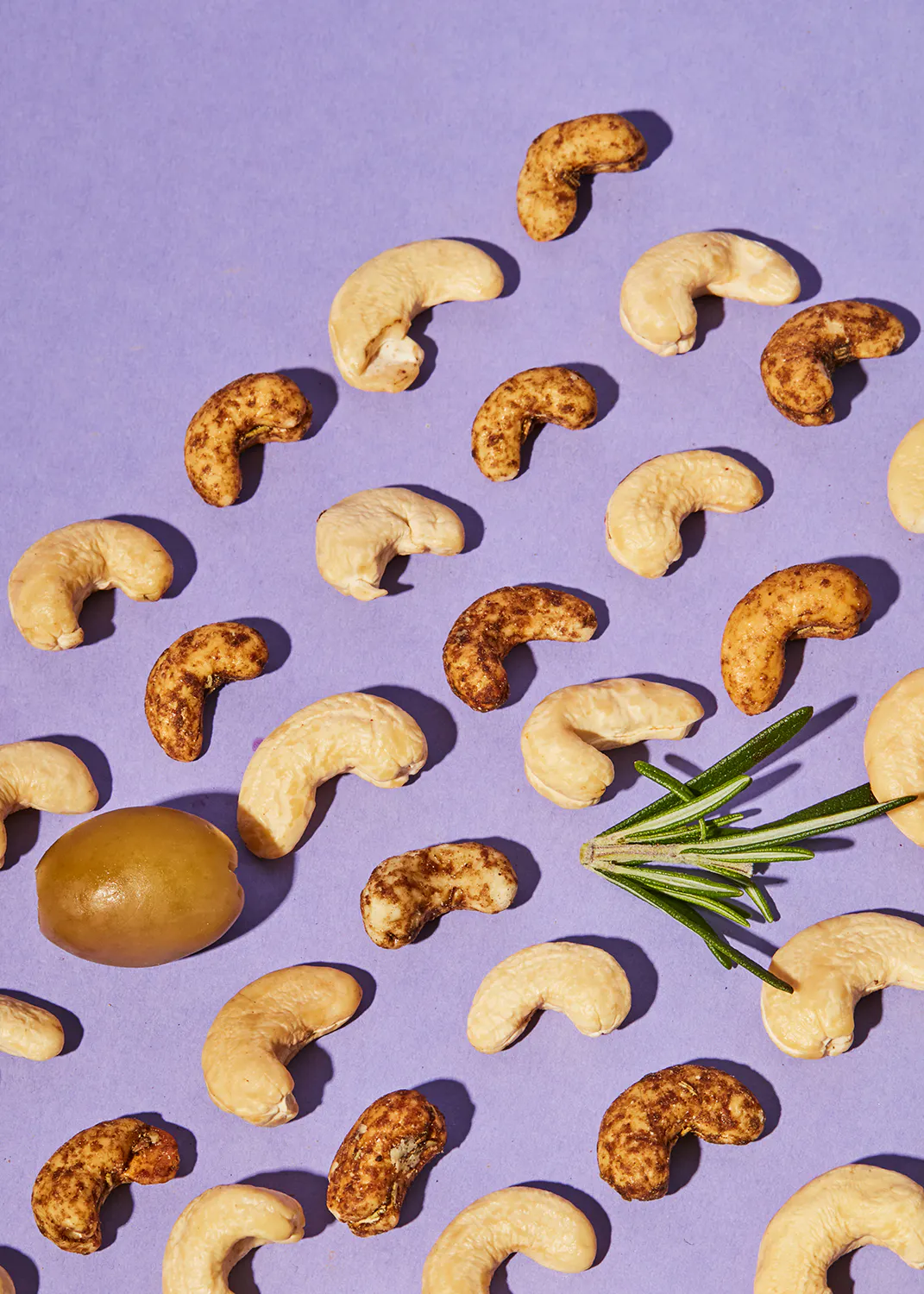 un tas de noix de cajou et d' olives sur un fond violet