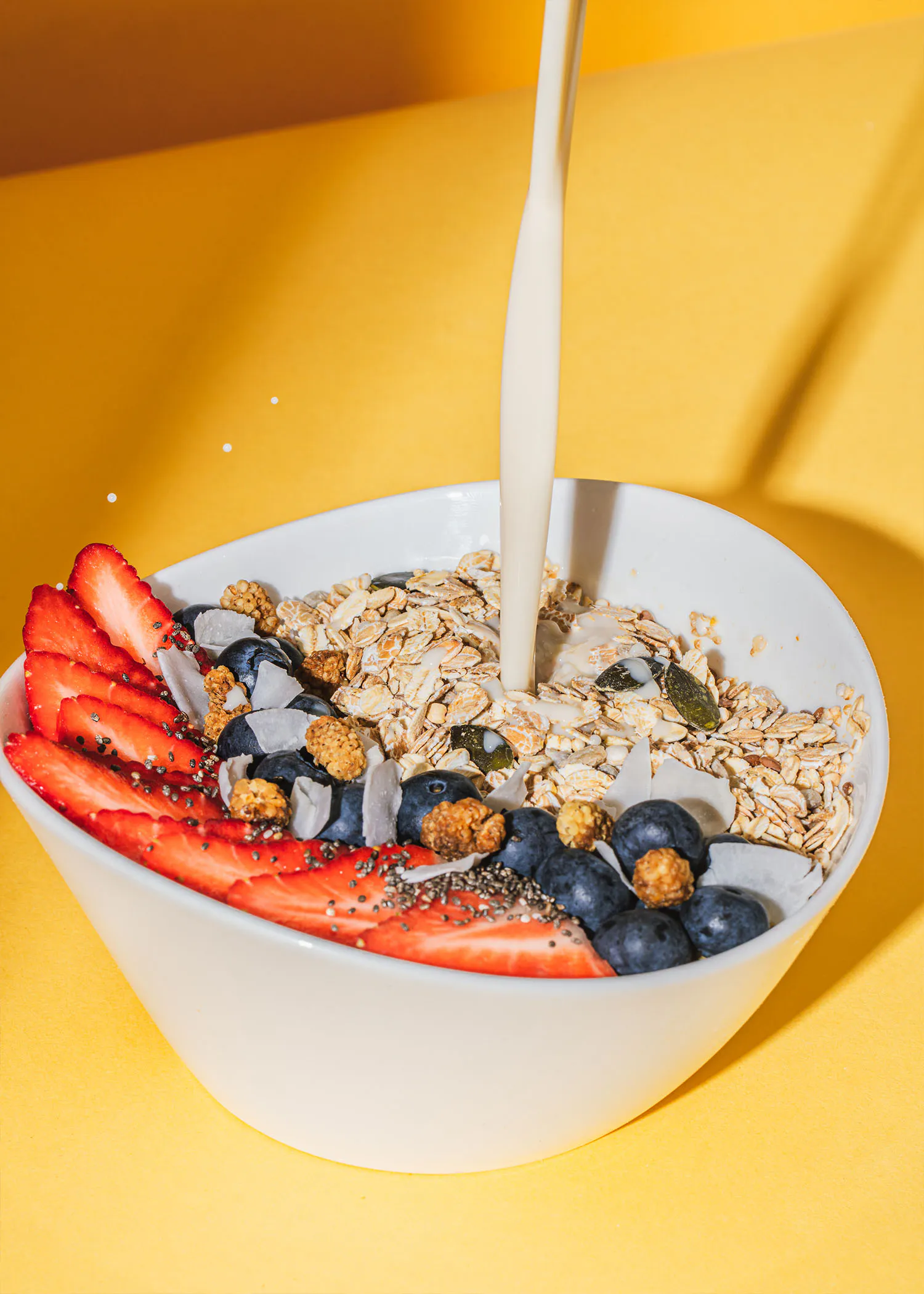 un bol de flocons d' avoine avec des fraises et des bleuets est versé avec du lait