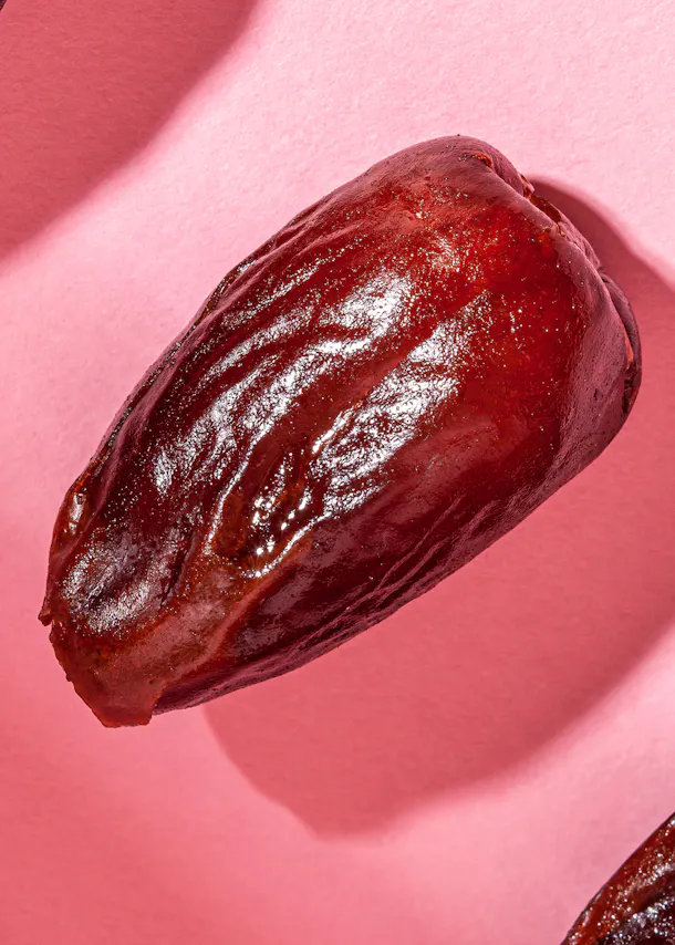 un gros plan d' une datte sur un fond rose