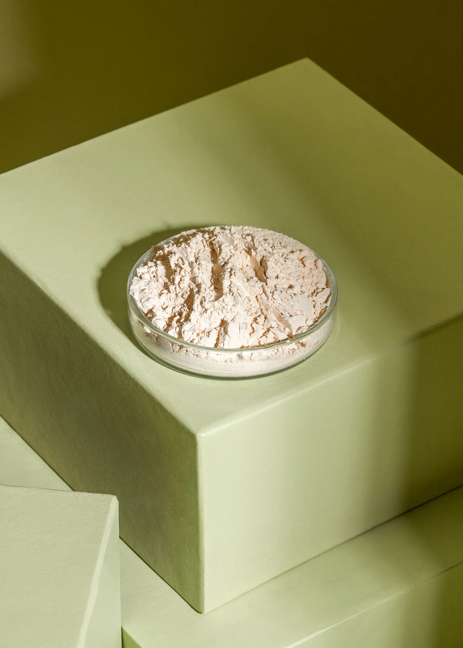 une assiette en verre remplie de poudre est posée sur une boîte verte