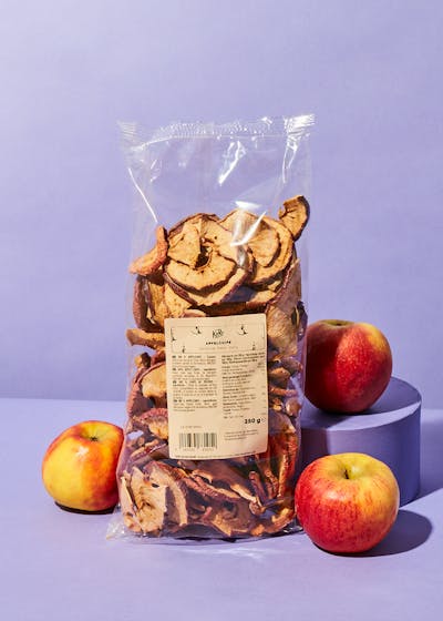 Apfelchips in Verpackung umgeben von frischen Äpfeln