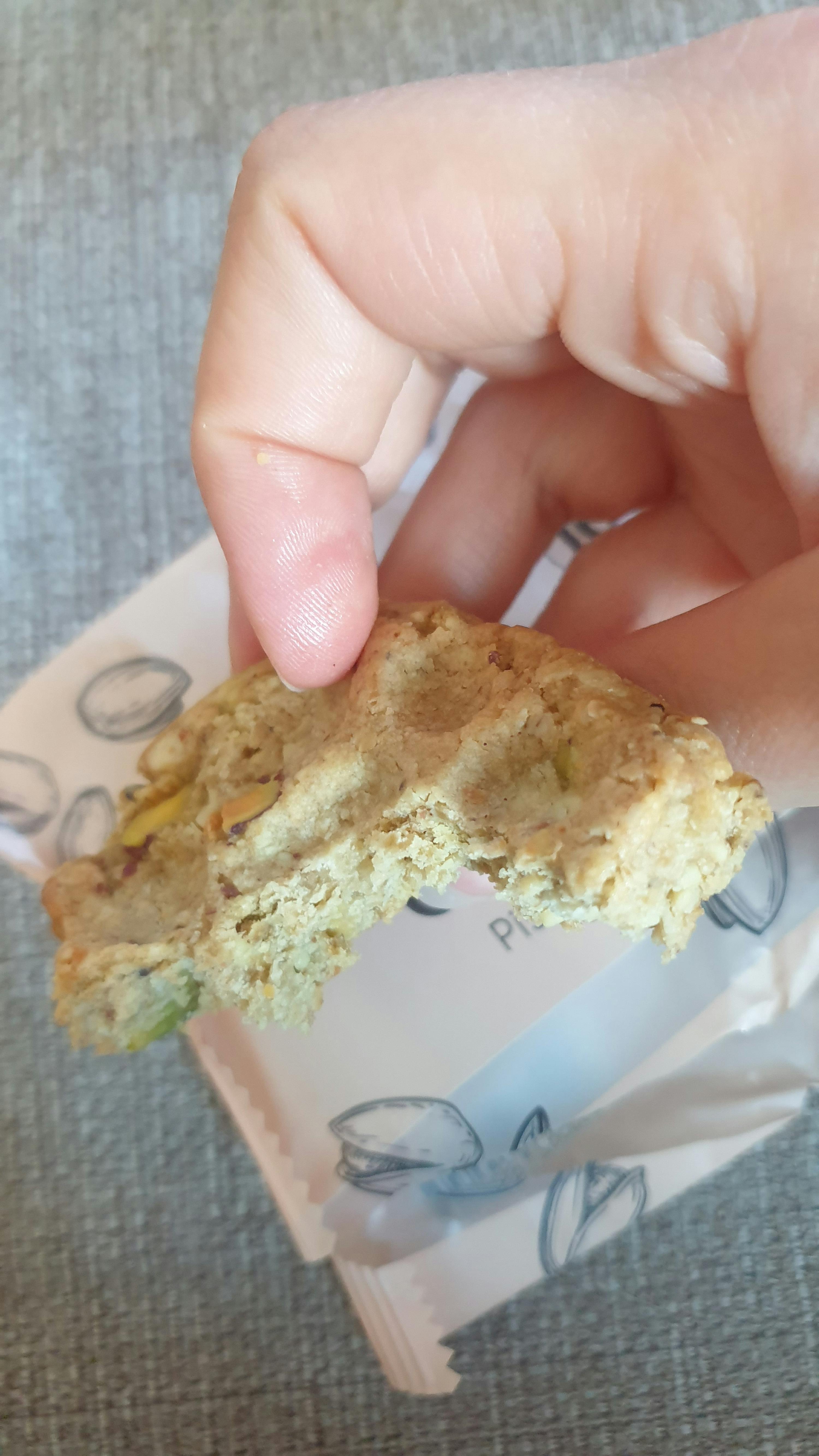 une personne tient un biscuit dans sa main avec une bouchée prise