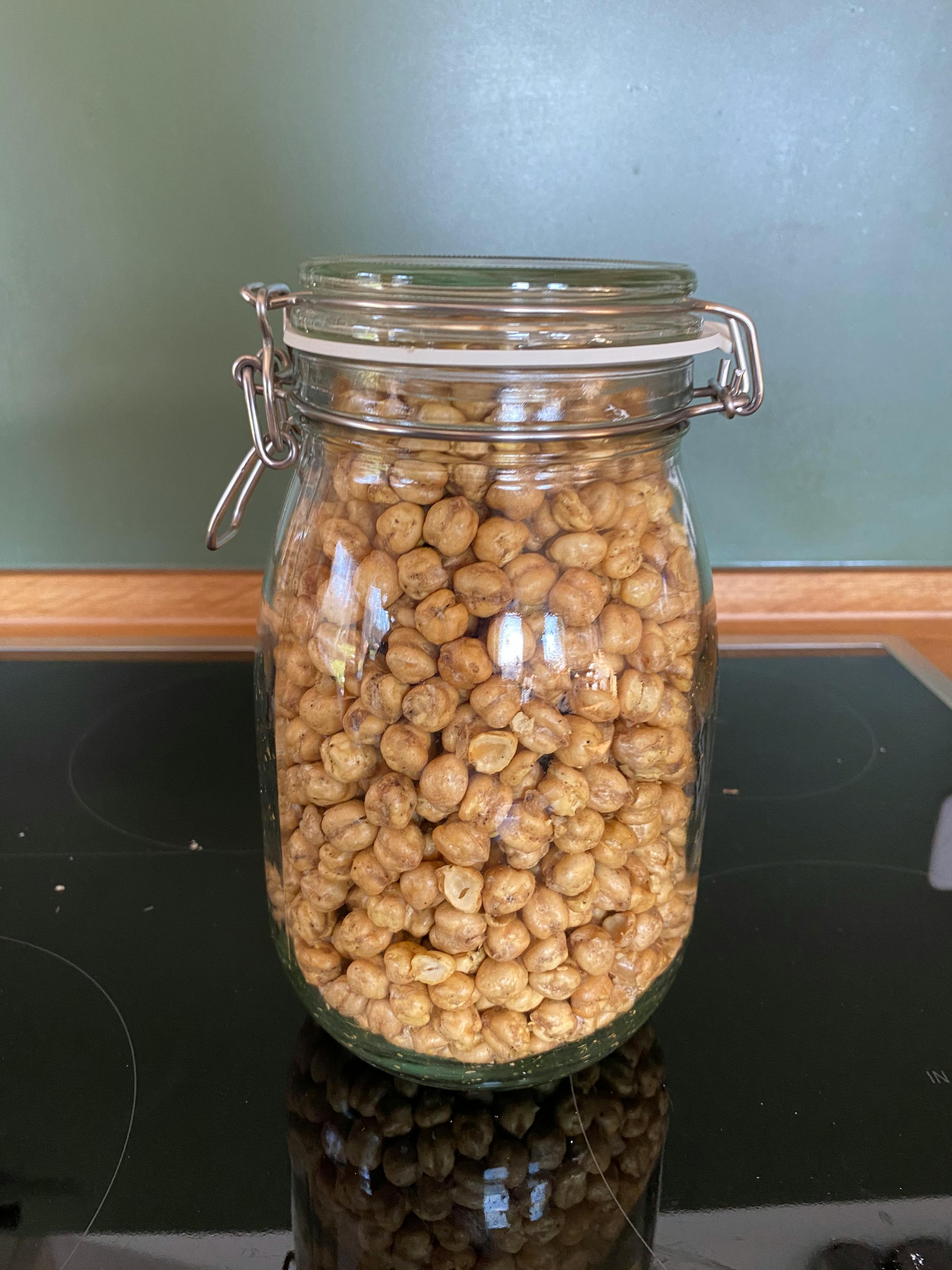 ein Glasgefäß gefüllt mit Kichererbsen steht auf einem Herd