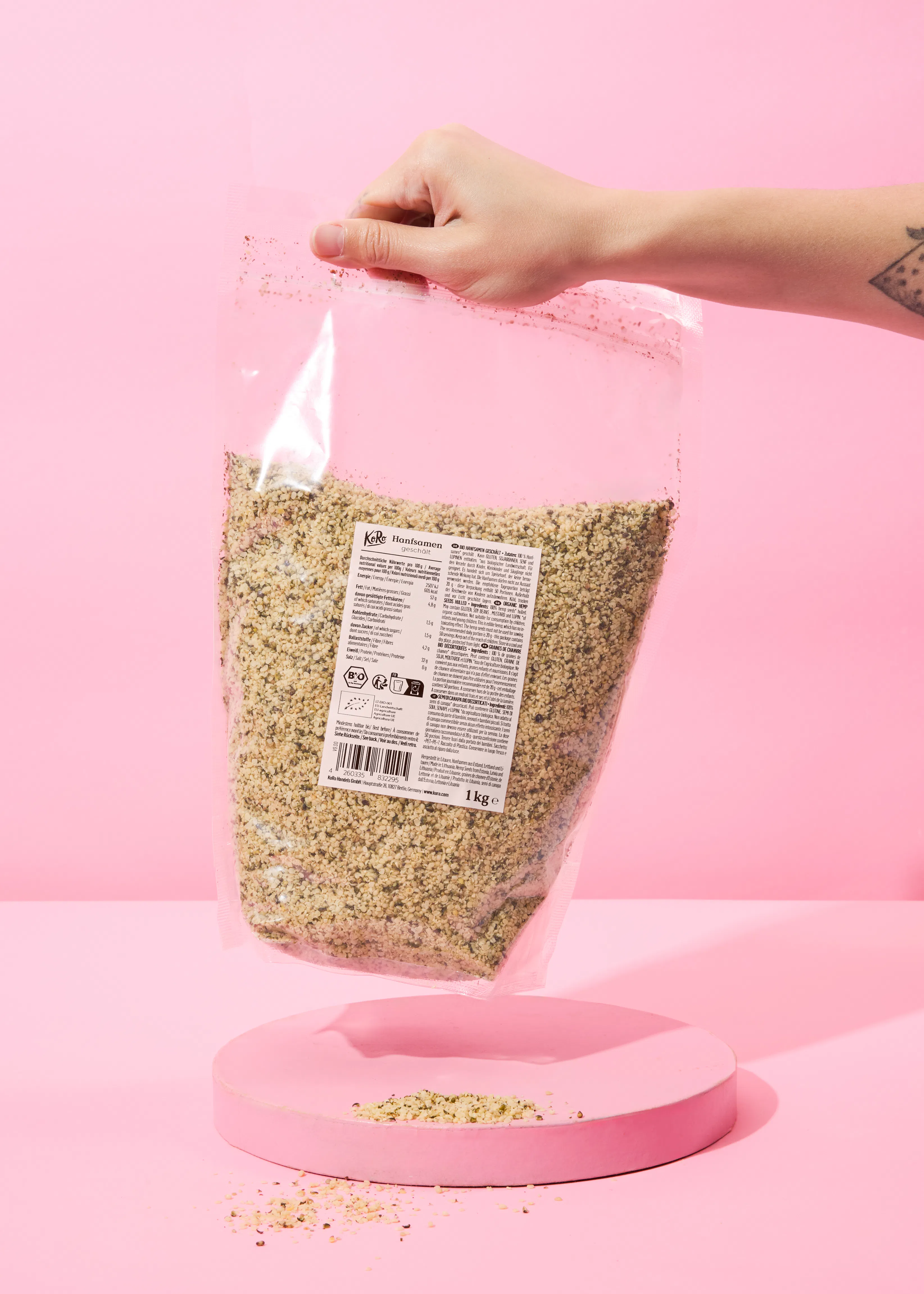 une personne tient un sac de graines de chanvre sur fond rose