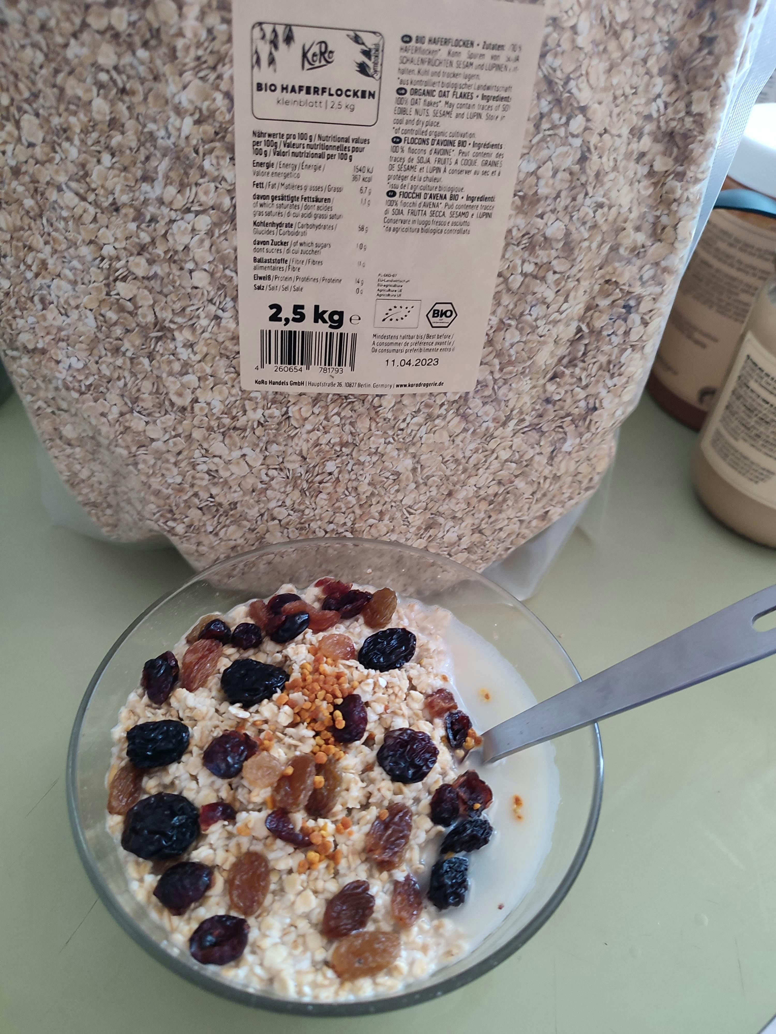 a bowl of cereal with raisins and honey next to a bag of oats