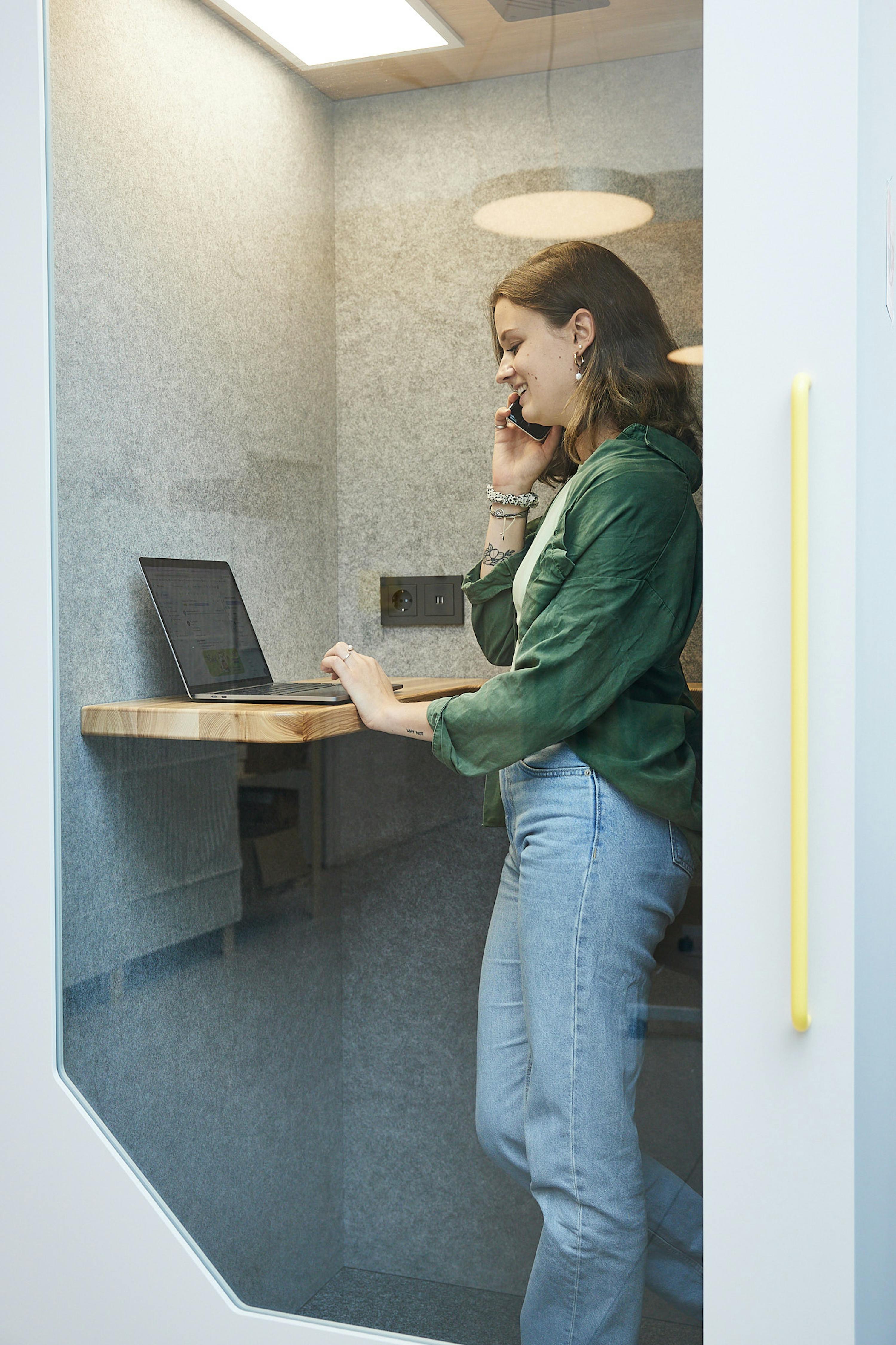 una donna sta parlando al cellulare in una cabina telefonica