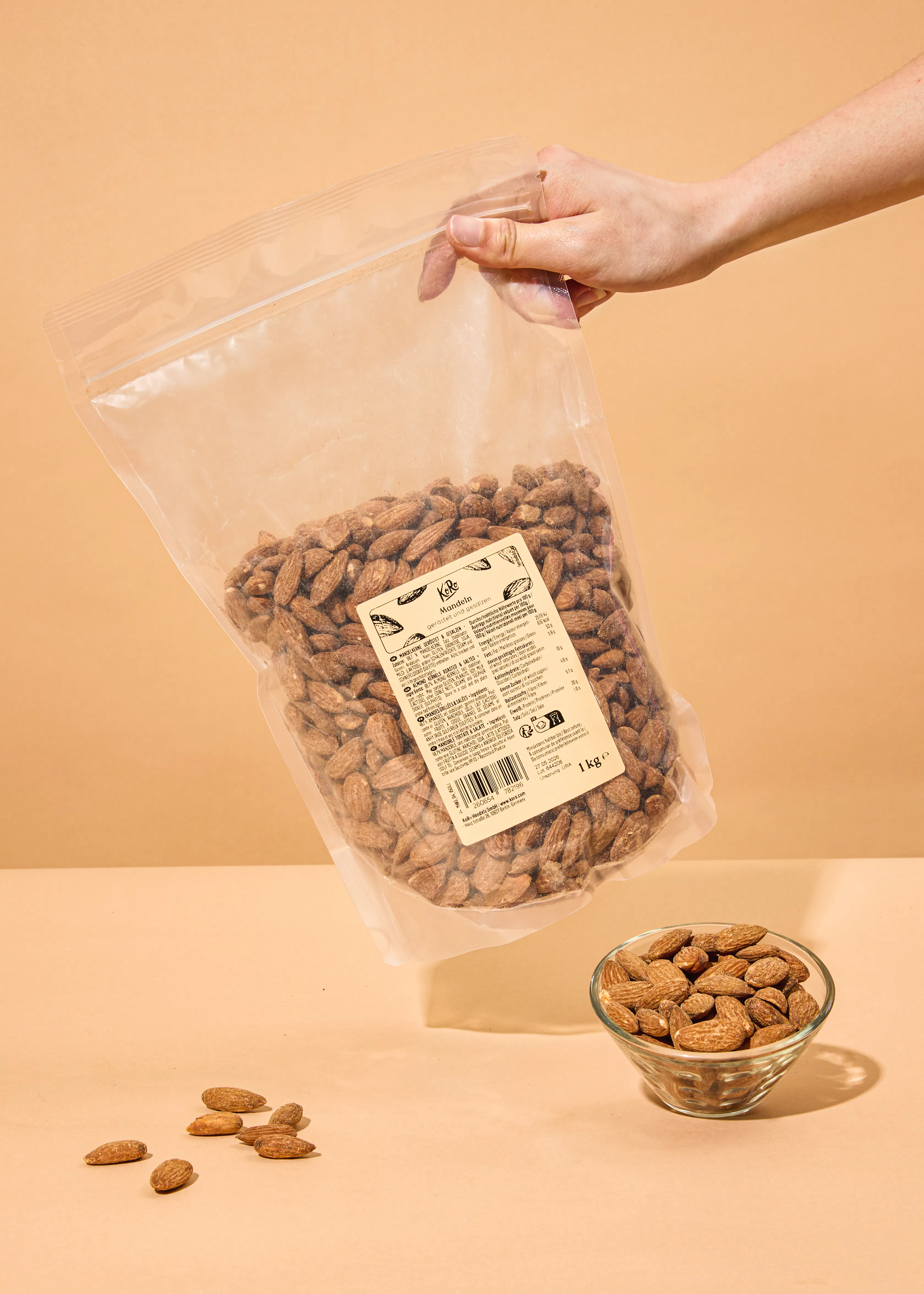 a person is holding a bag of almonds next to a glass bowl of almonds
