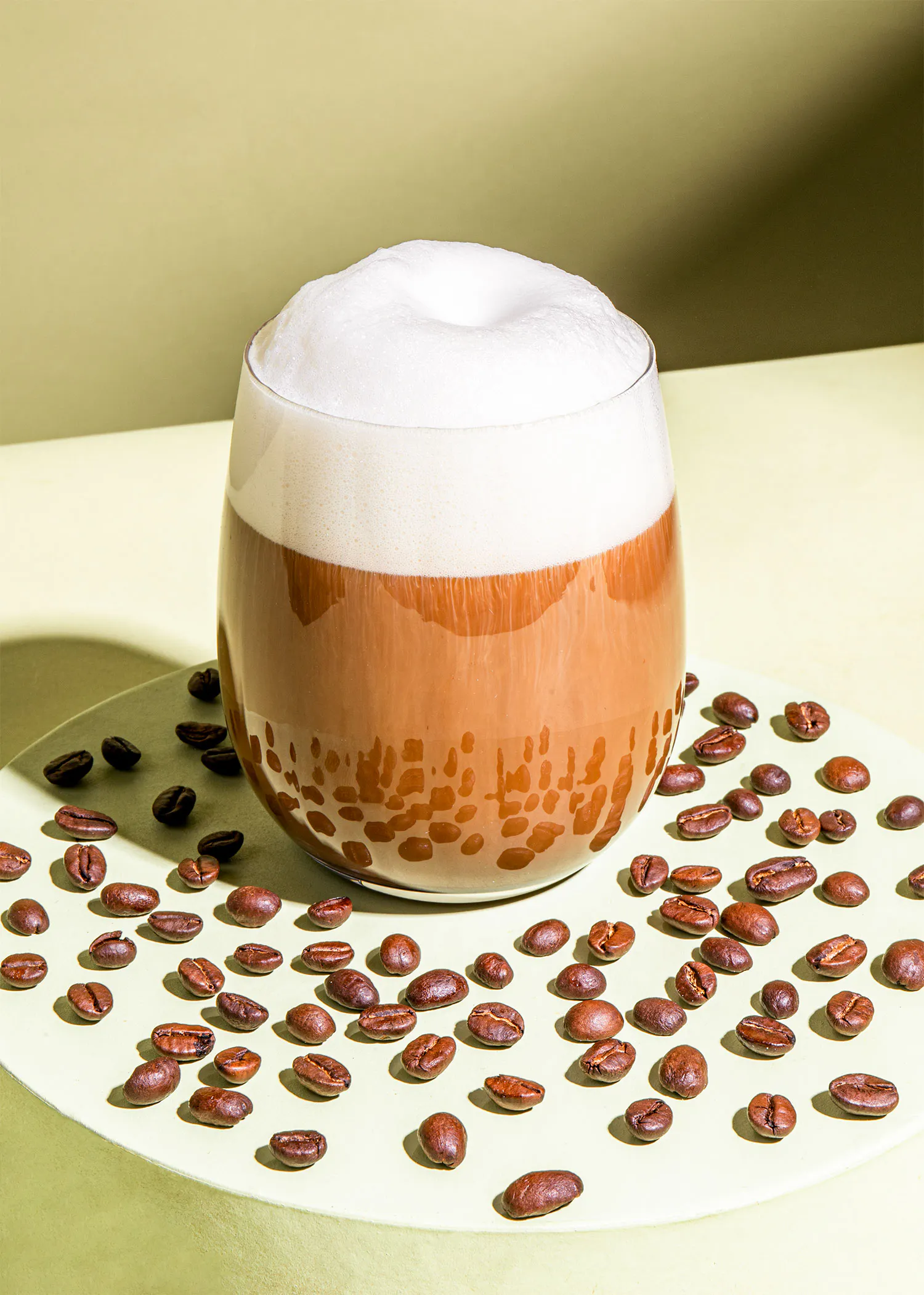 un verre de café entouré de grains de café sur une assiette