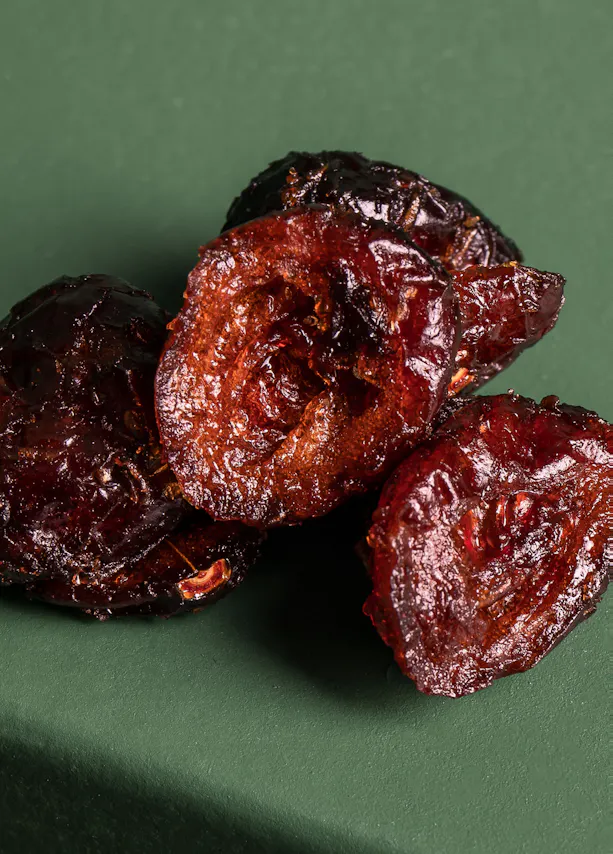 une pile de prunes séchées sur une surface verte