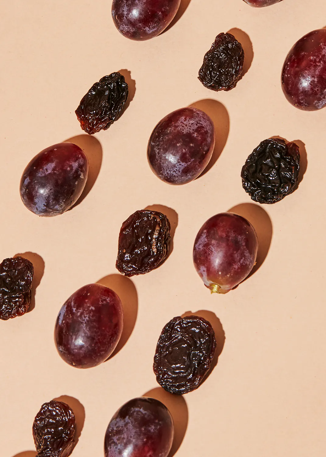 a bunch of grapes and raisins on a beige surface