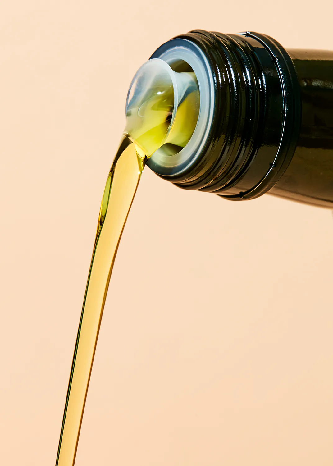a bottle of olive oil is being poured into a container