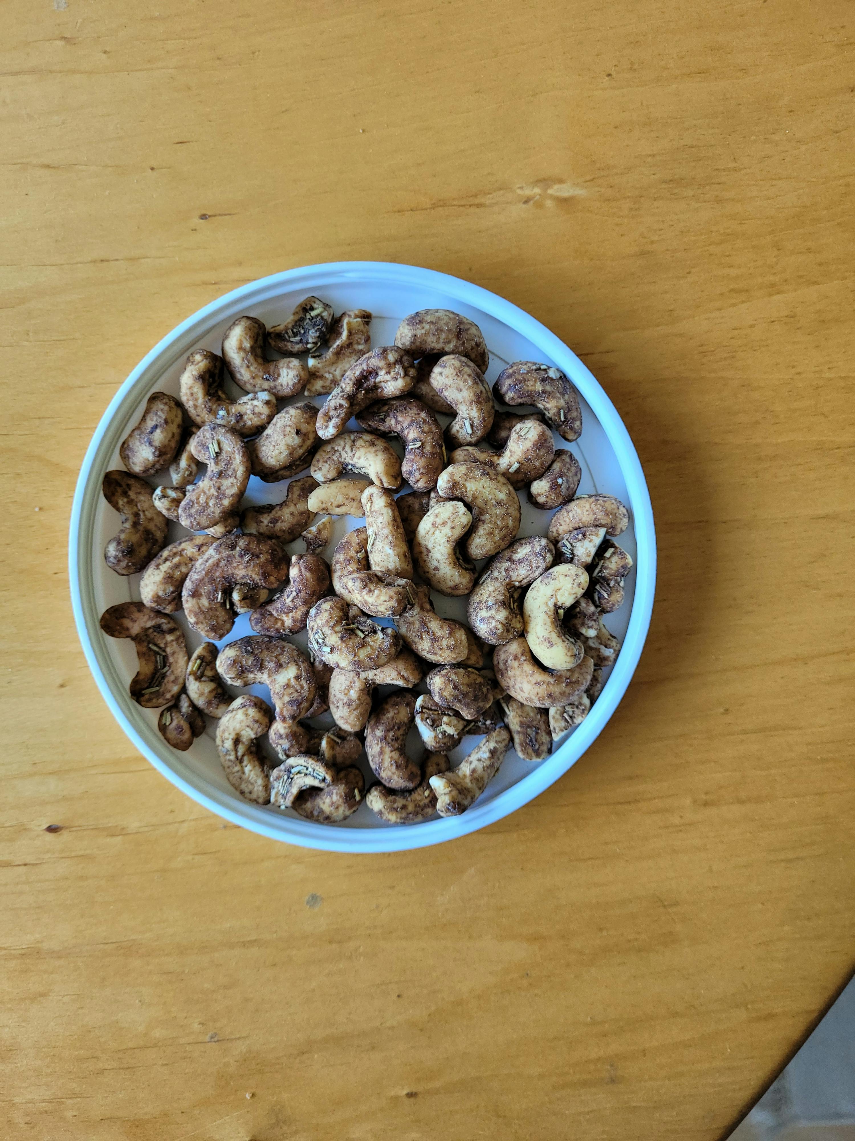 una ciotola bianca piena di anacardi su un tavolo di legno