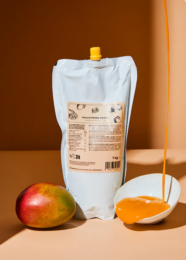 un sac de purée de mangue est assis à côté d' une mangue