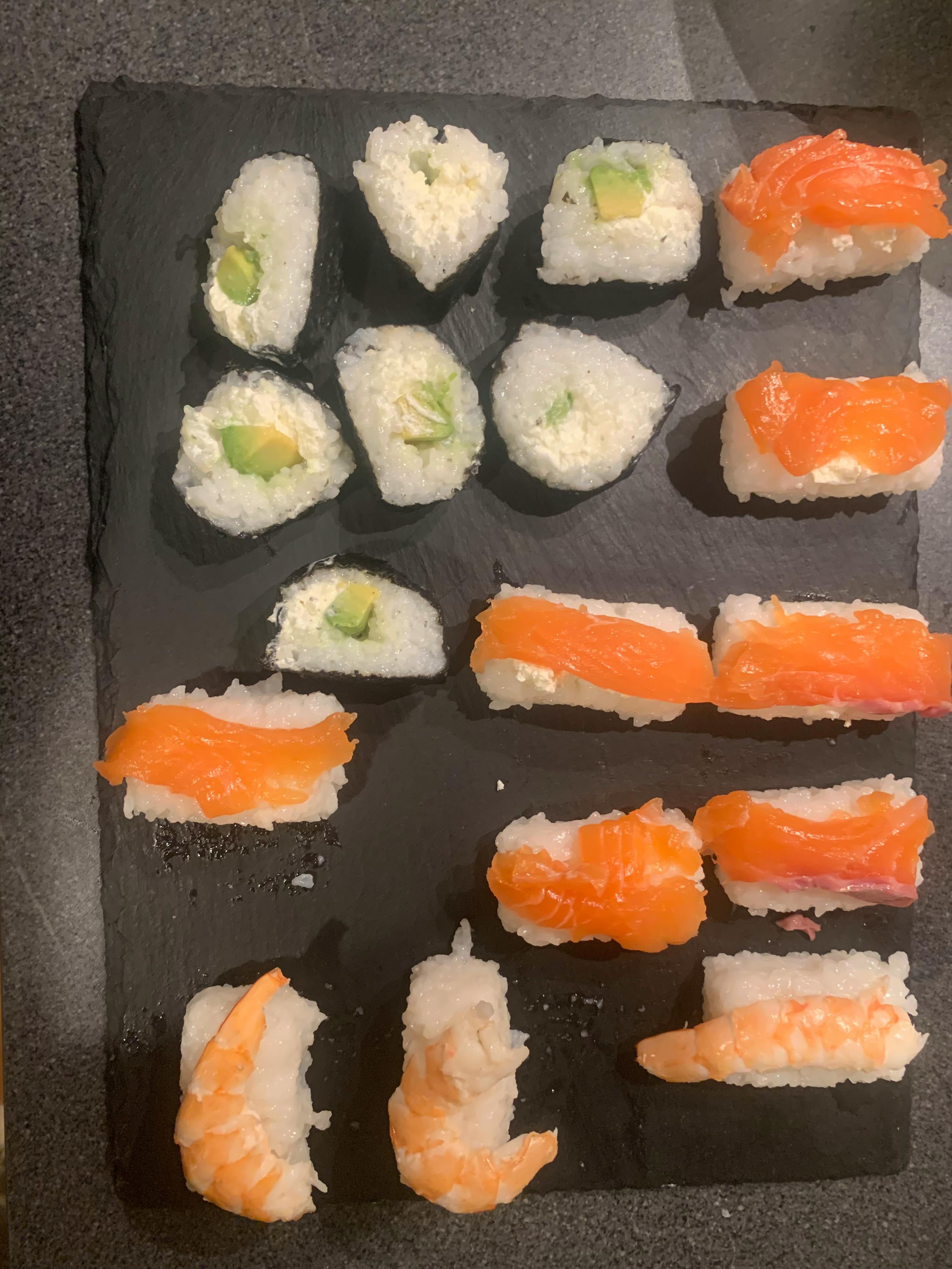 a variety of sushi including salmon and shrimp on a black plate