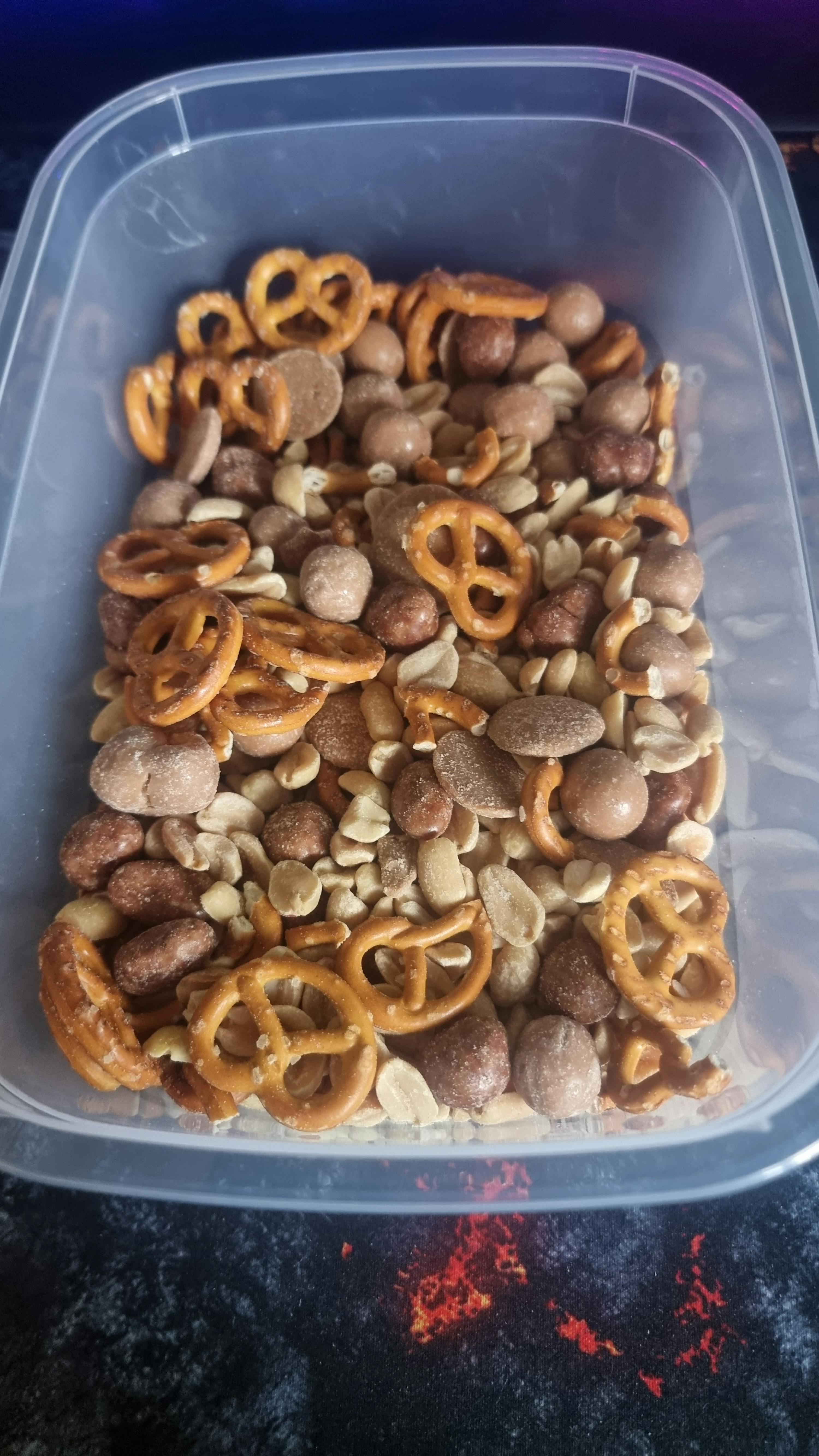 un récipient en plastique rempli de noix et de bretzels