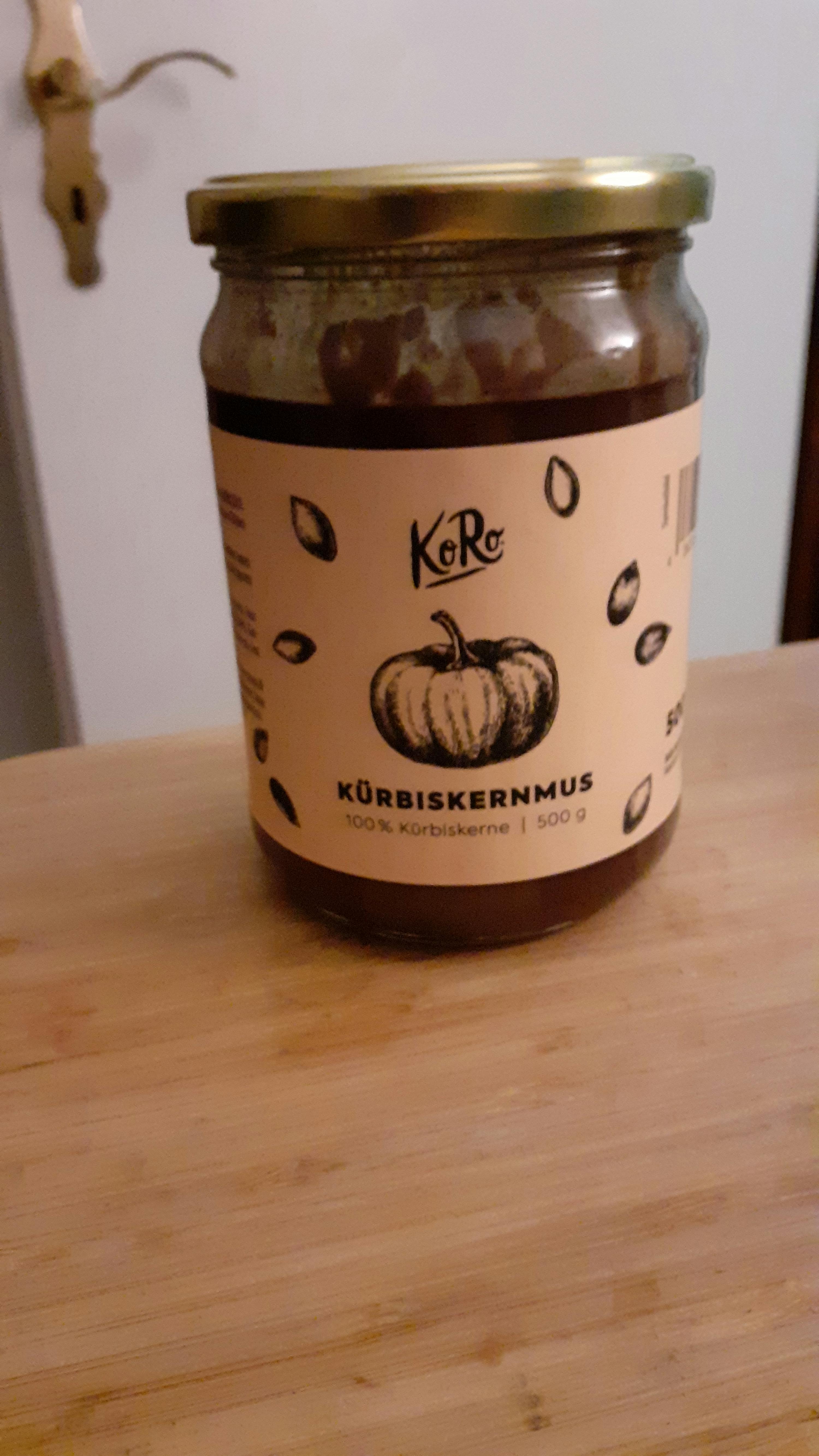 a jar of kurbiskernmus is sitting on a wooden table