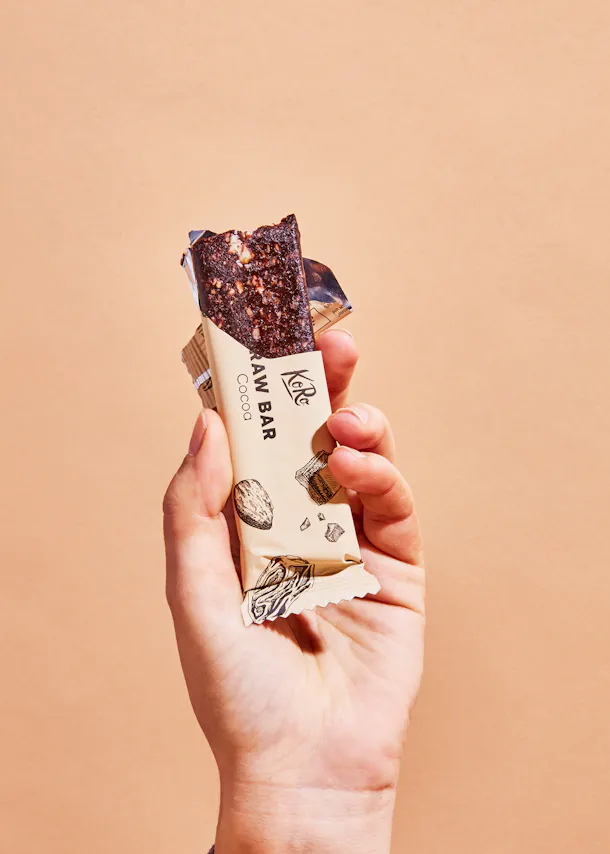 une personne tient une barre de cacao crue dans sa main