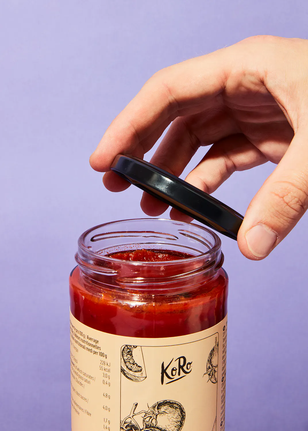 une personne tient le couvercle d' un bocal de ketchup