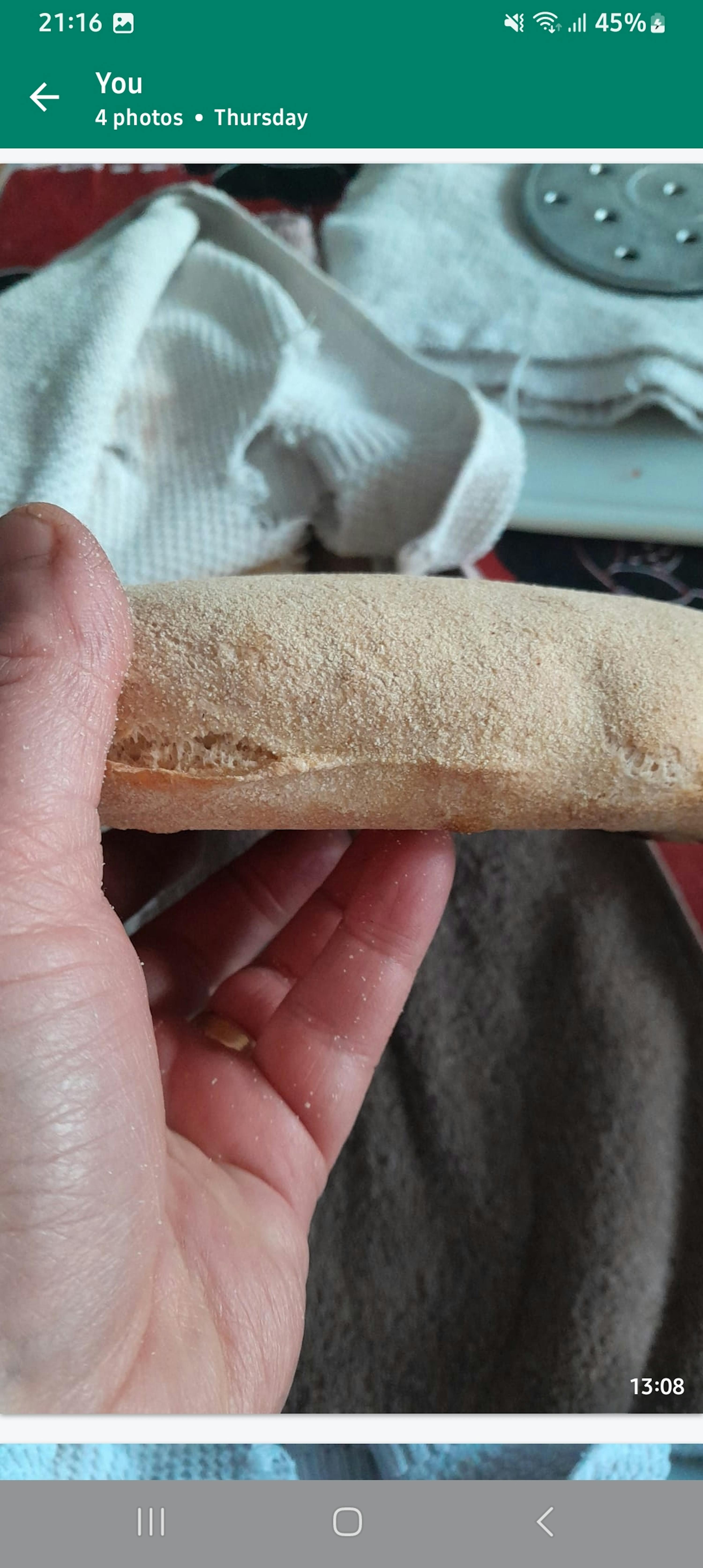 a person is holding a piece of bread in their hand and the time is 13:58