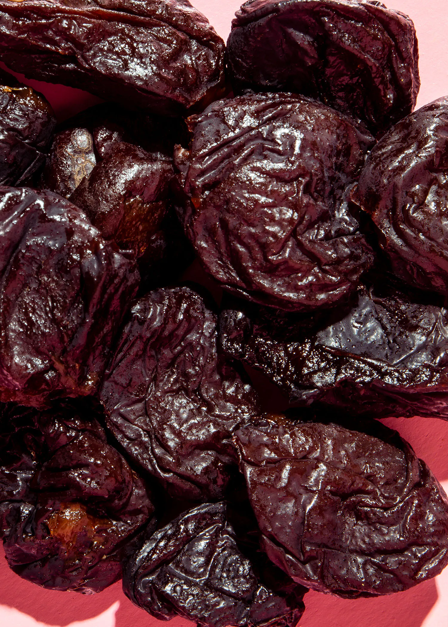 une pile de prunes séchées sur fond rose