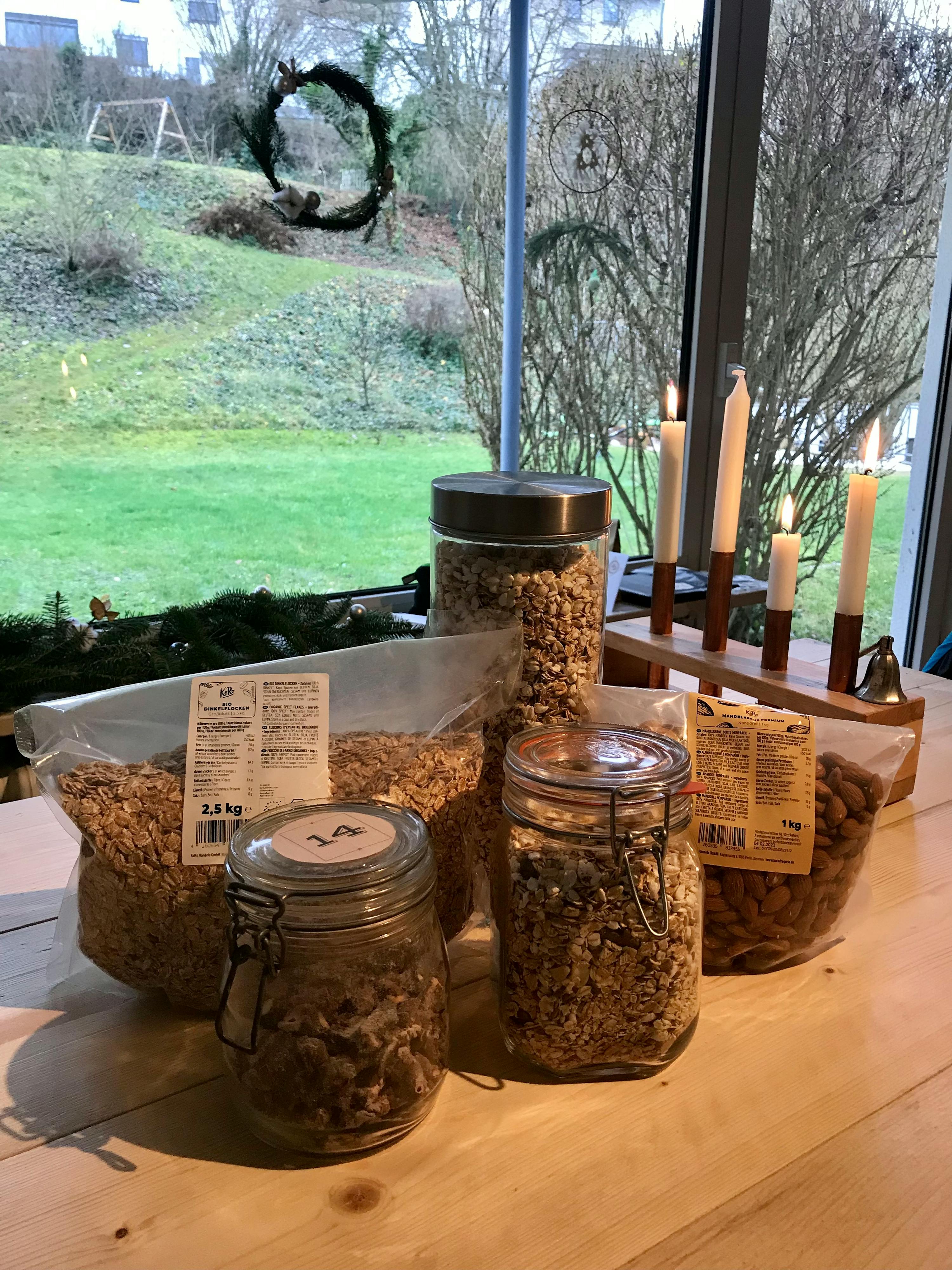 Auf einem Holztisch stehen verschiedene Gläser mit Müsli und Mandeln