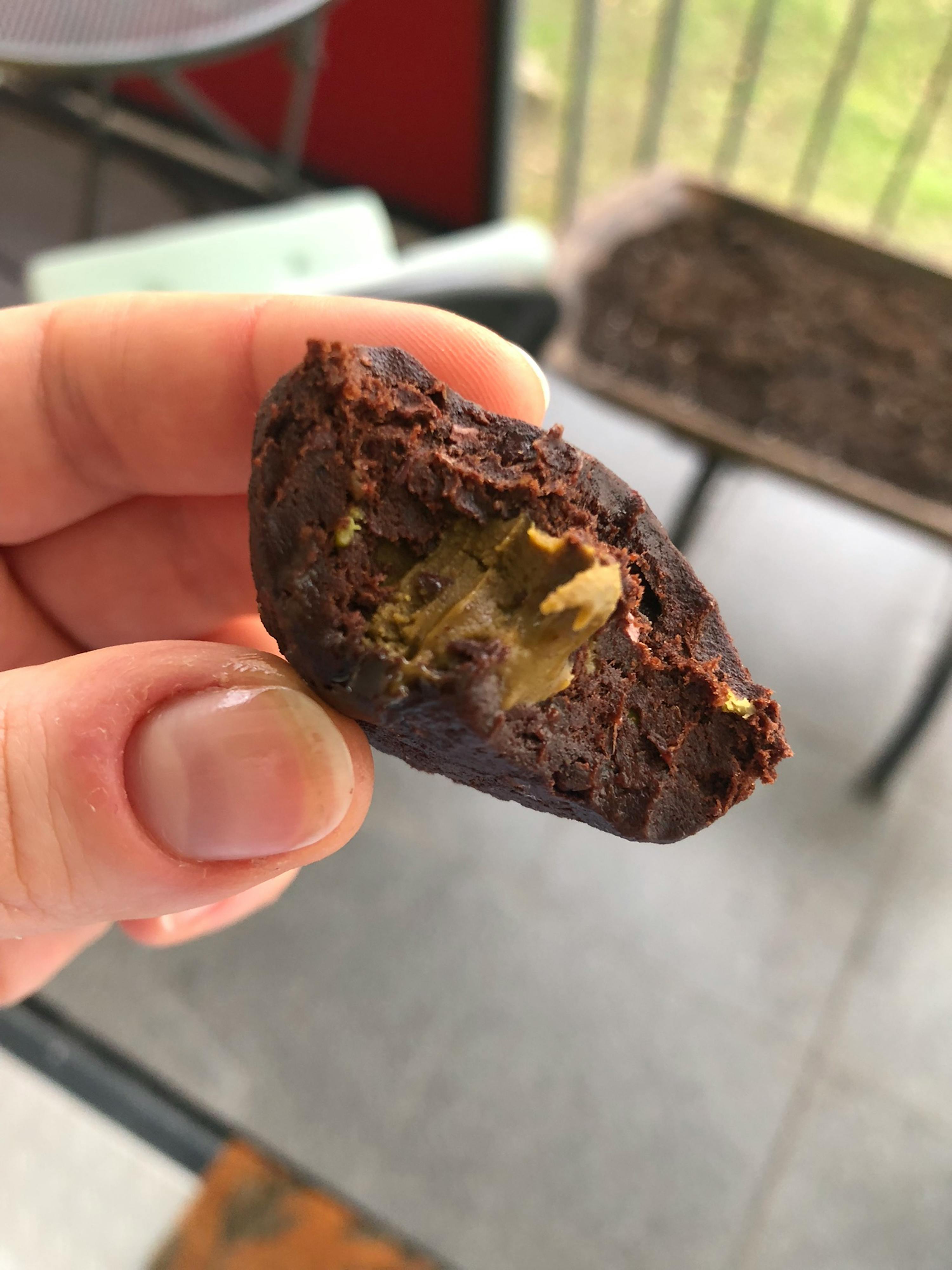 una persona tiene in mano un biscotto al cioccolato con burro di arachidi dentro