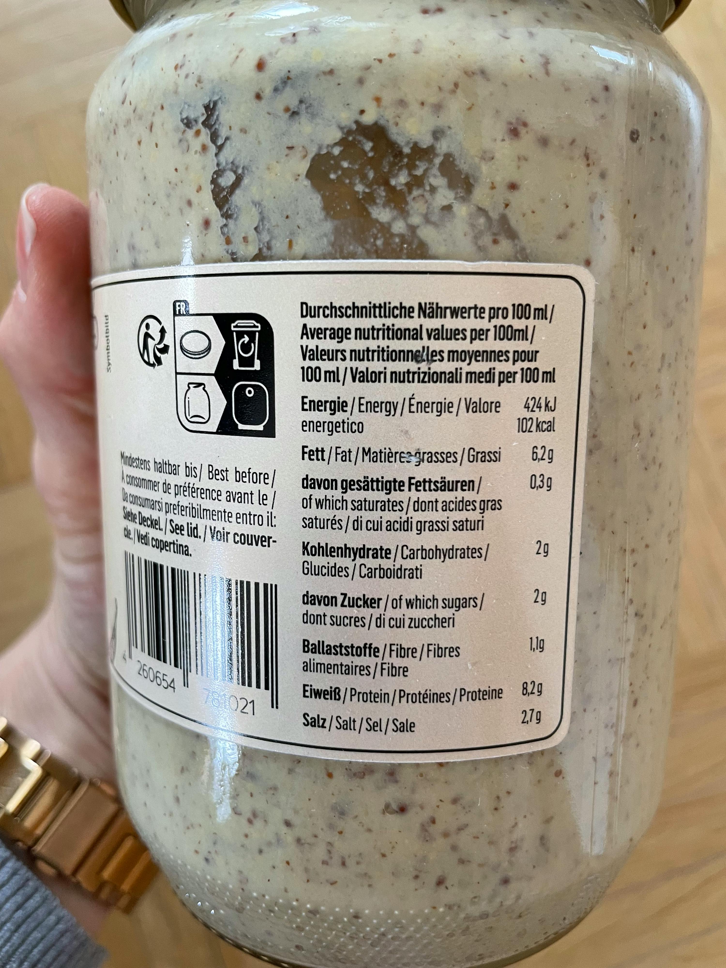 une personne tient un bocal de moutarde avec une étiquette de nutrition