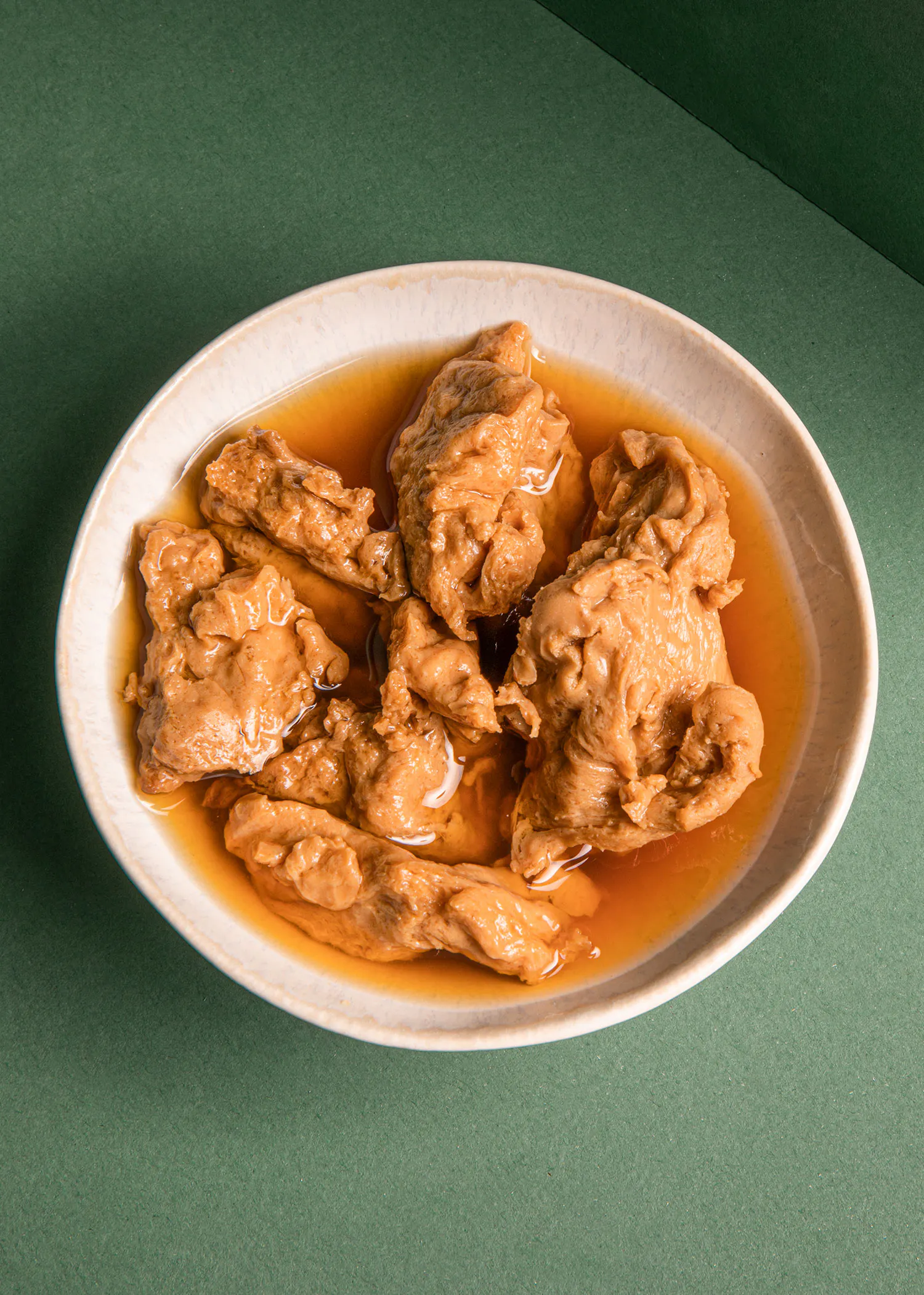 ein weißer Teller mit braunem Fleisch in einer Soße