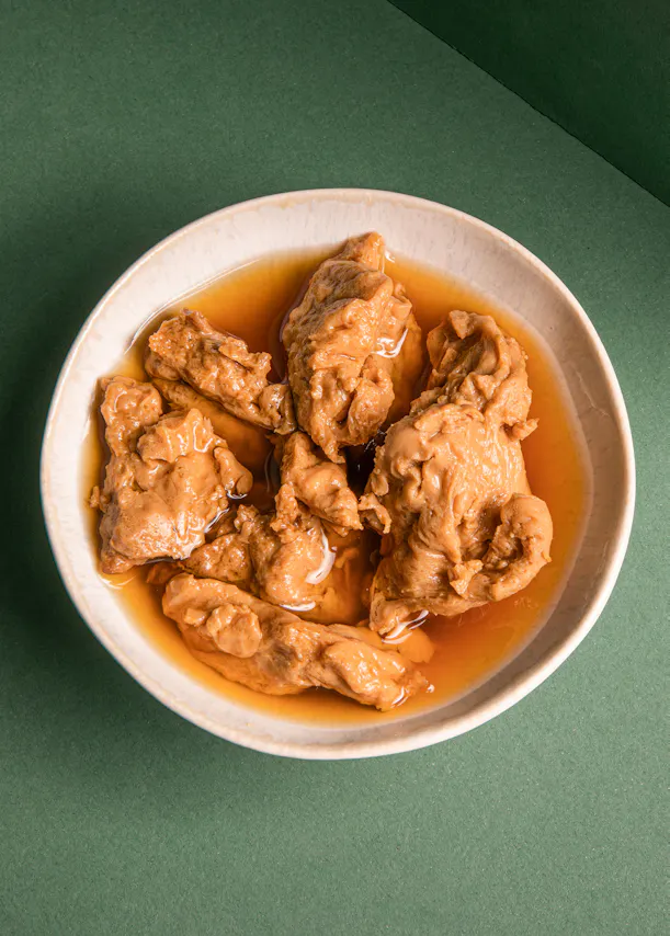 ein weißer Teller mit braunem Fleisch in einer Soße