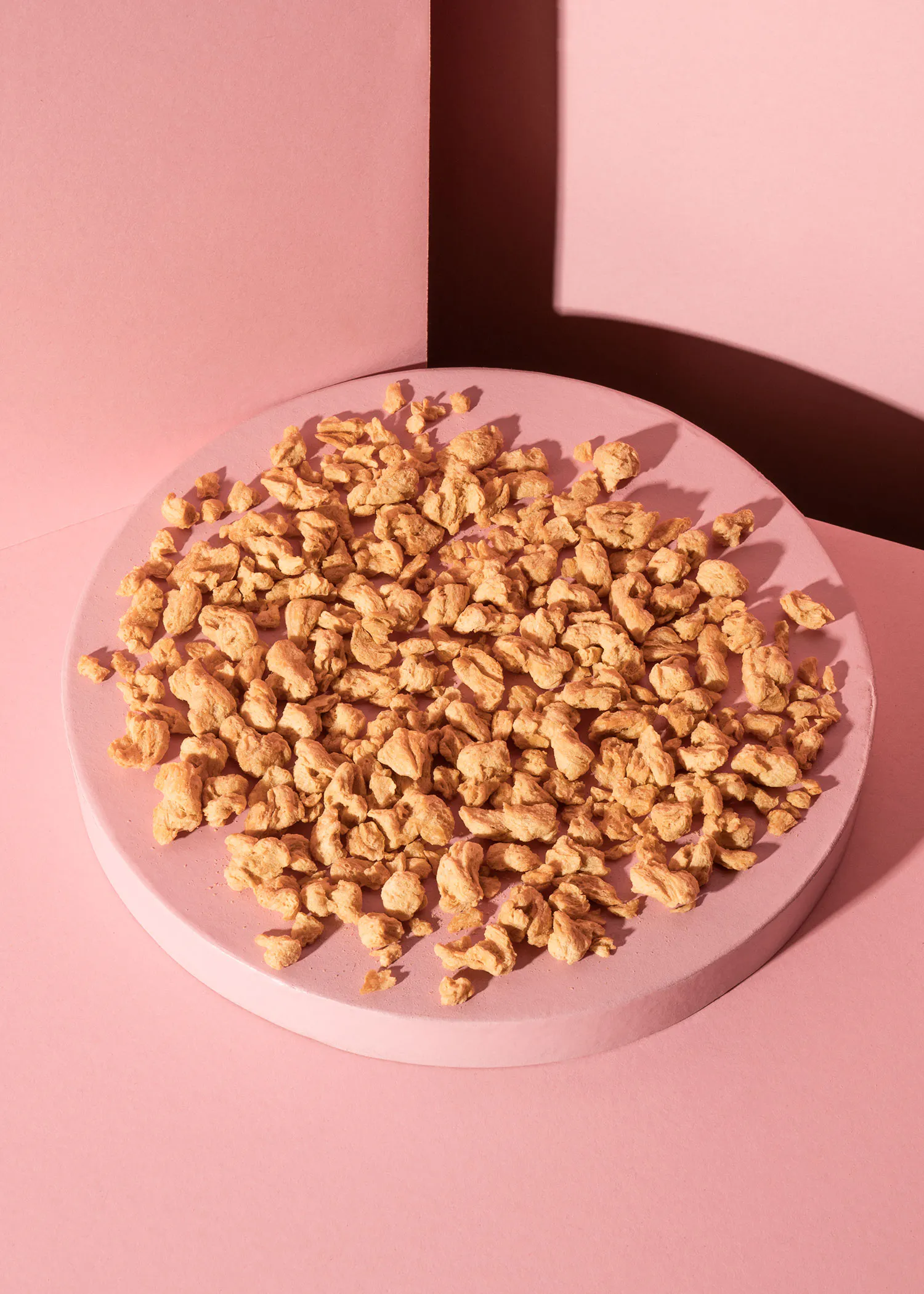 une assiette ronde remplie de noix sur un fond rose