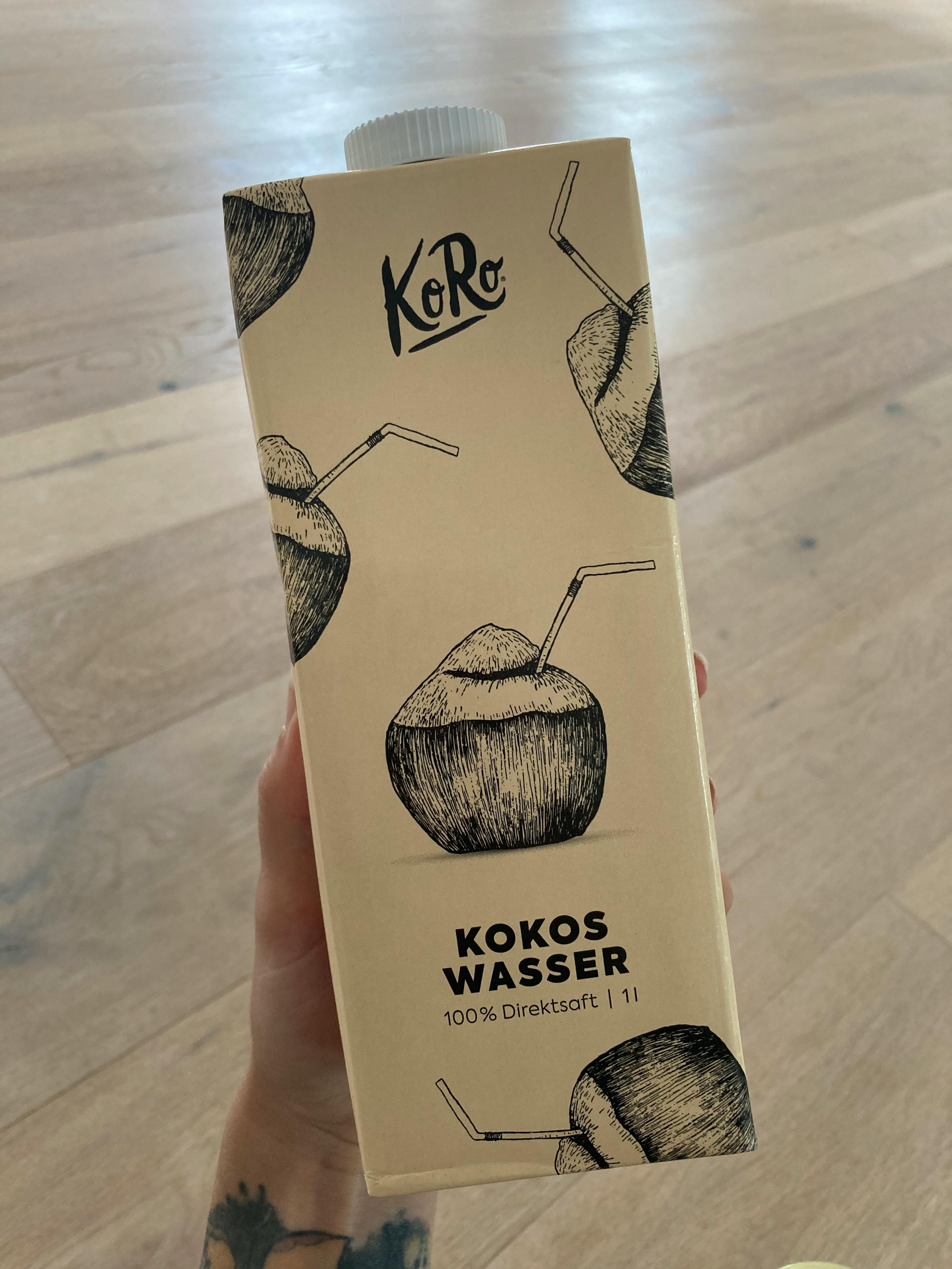 a person holding a carton of kokos wasser