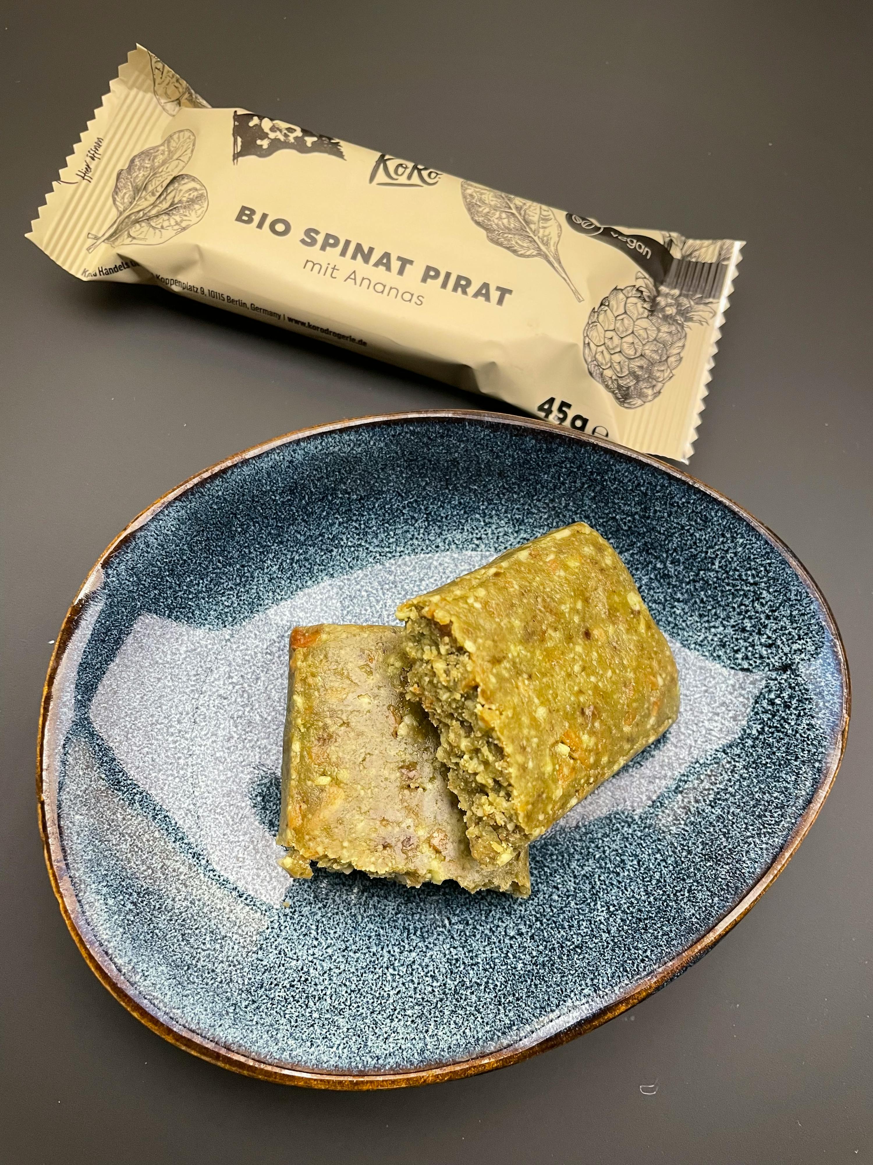 a piece of food on a plate next to a bio spinat pirat bar