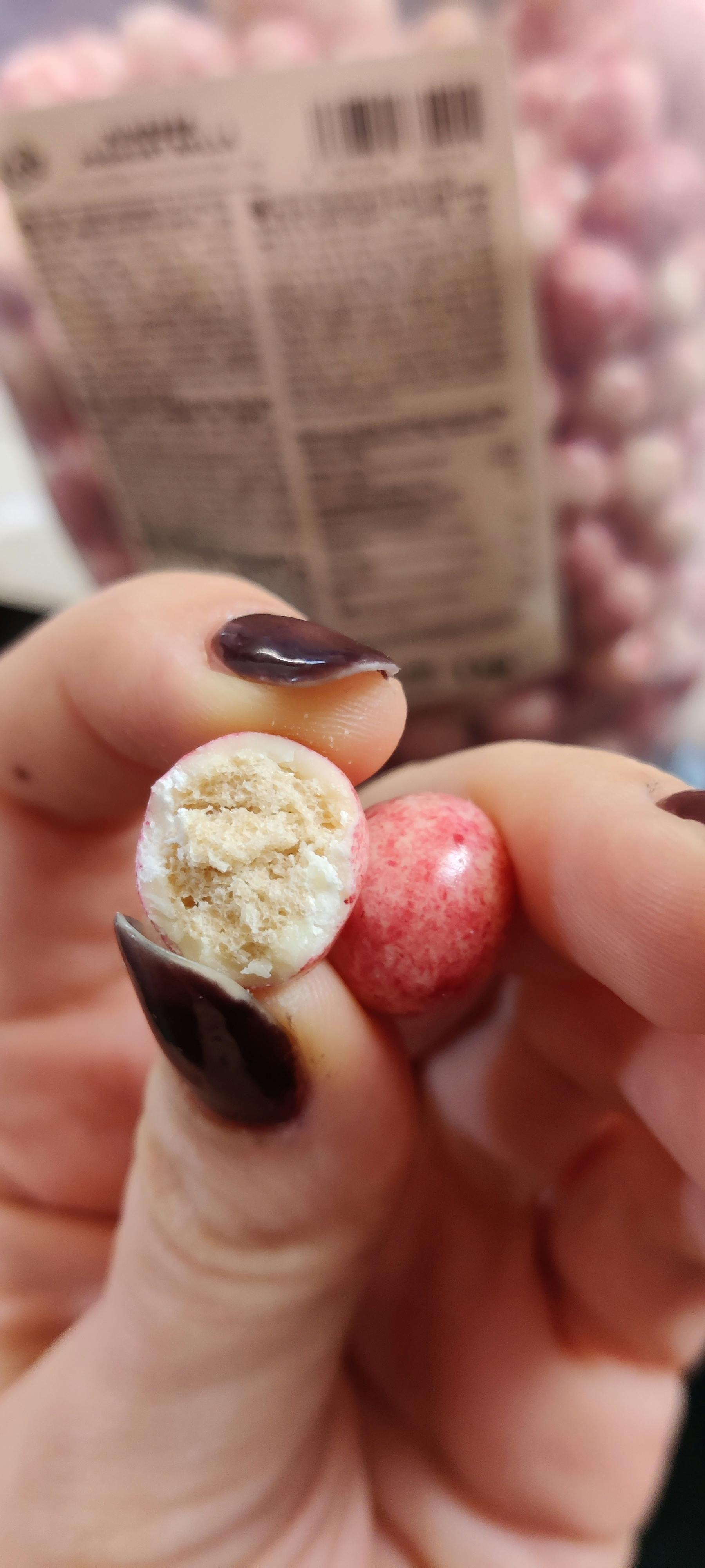 a close up of a person holding a candy with a bite taken out of it